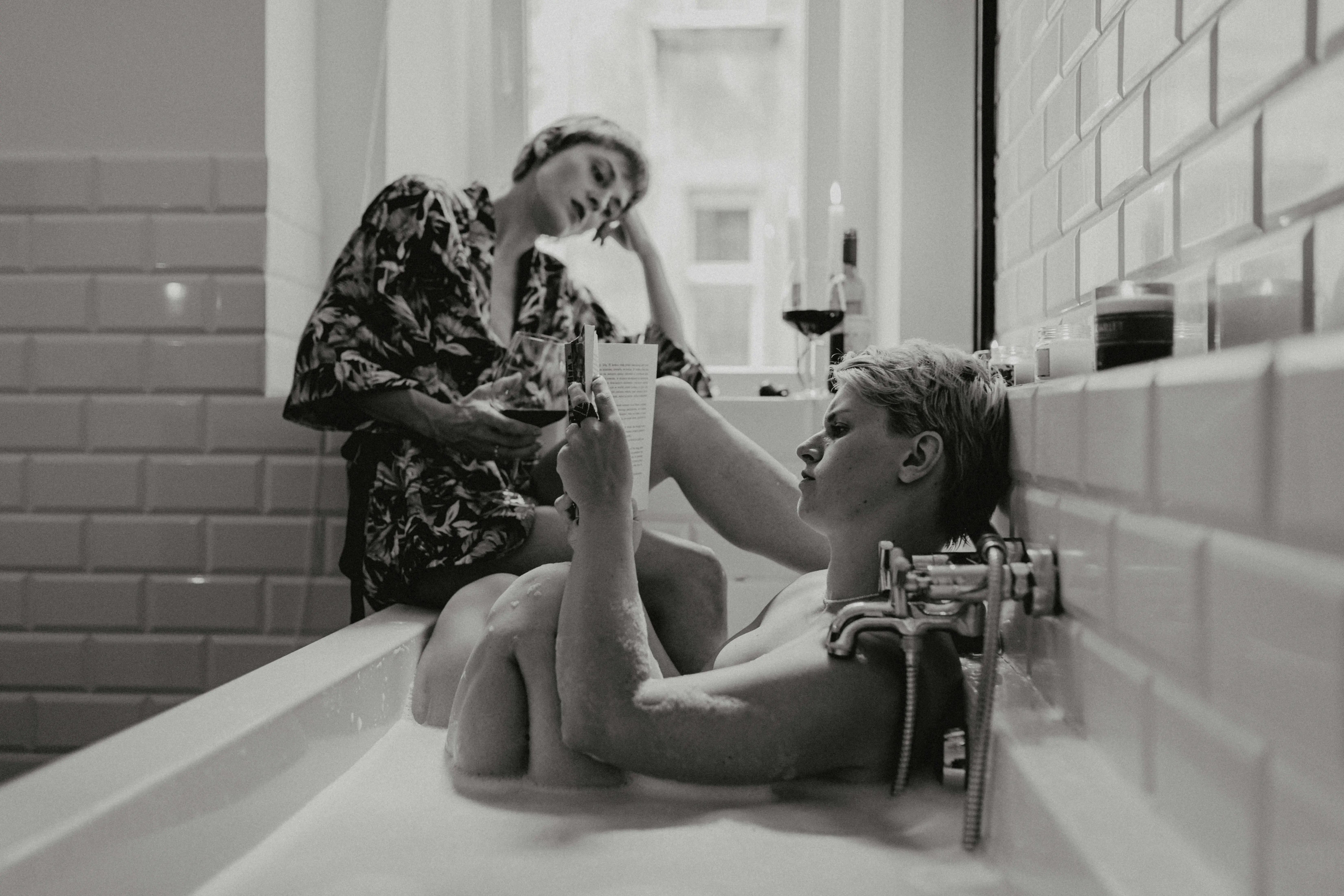 concrete bird bath Two women enjoy a relaxing bath together, reading and sipping wine in a cozy atmosphere.