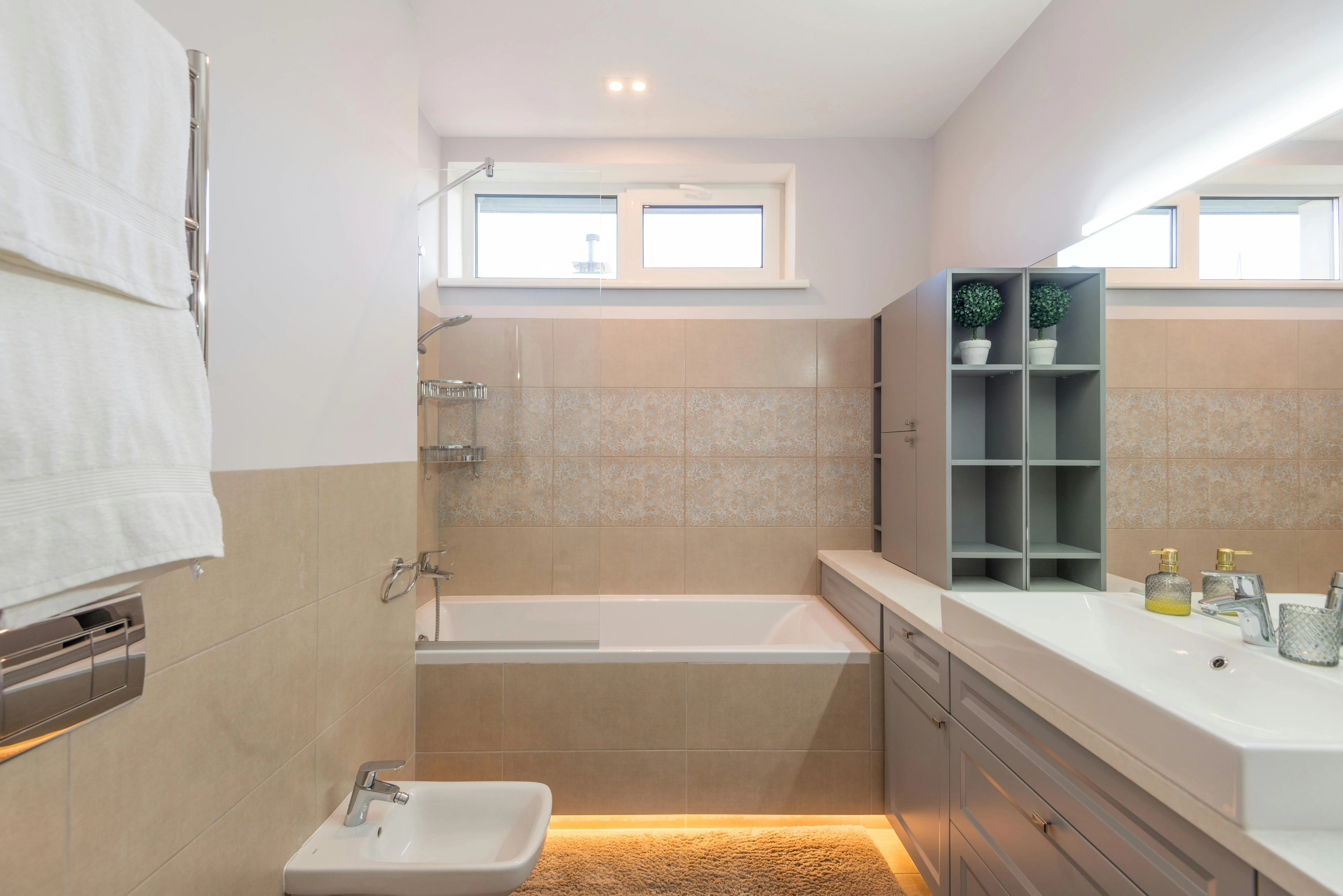 shower shelf Contemporary beige bathroom featuring a bathtub, sink, and stylish mirror with ample lighting.