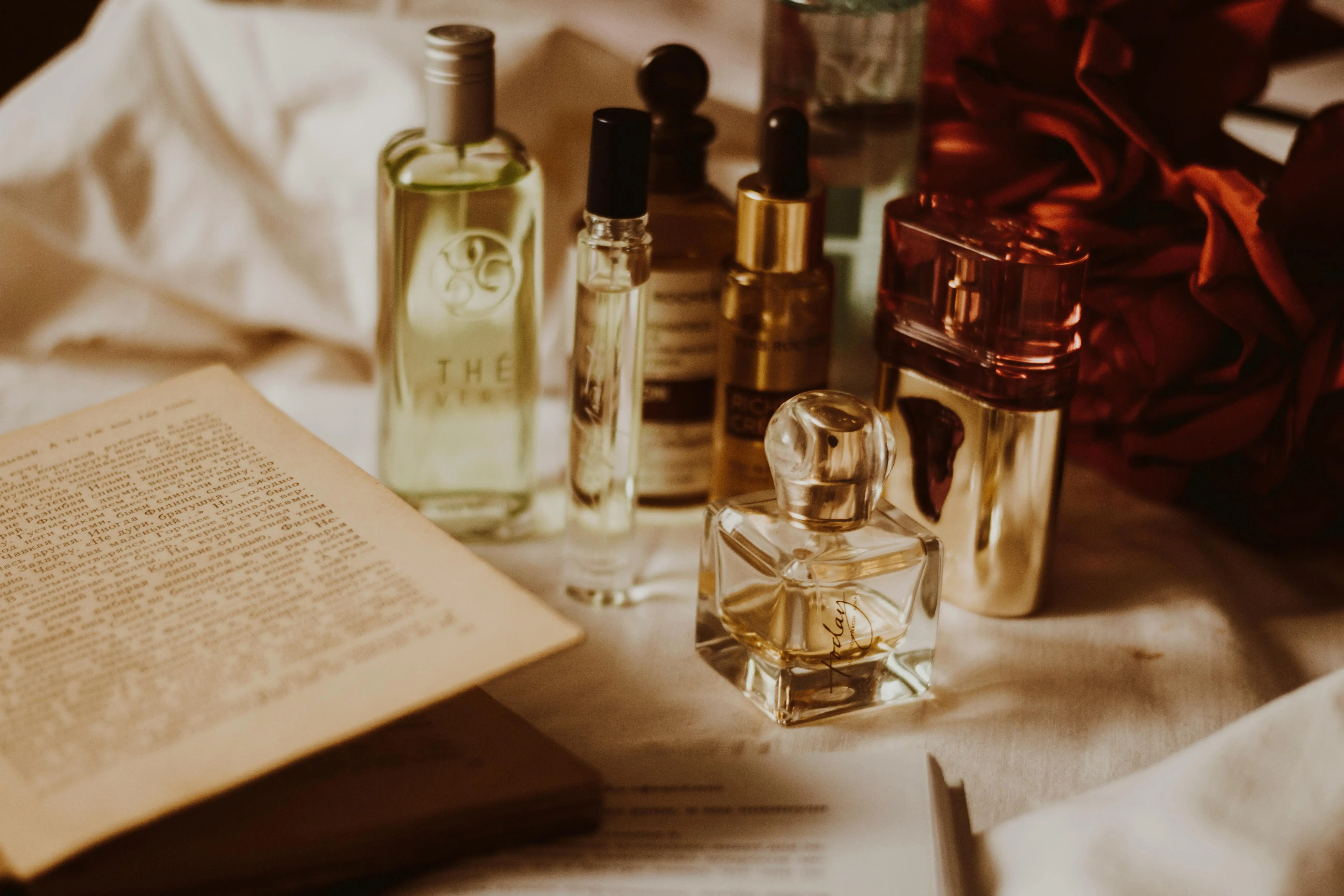 what might protect your shirt from a grease stain Aesthetic still life of assorted perfume bottles and an open book on a table.