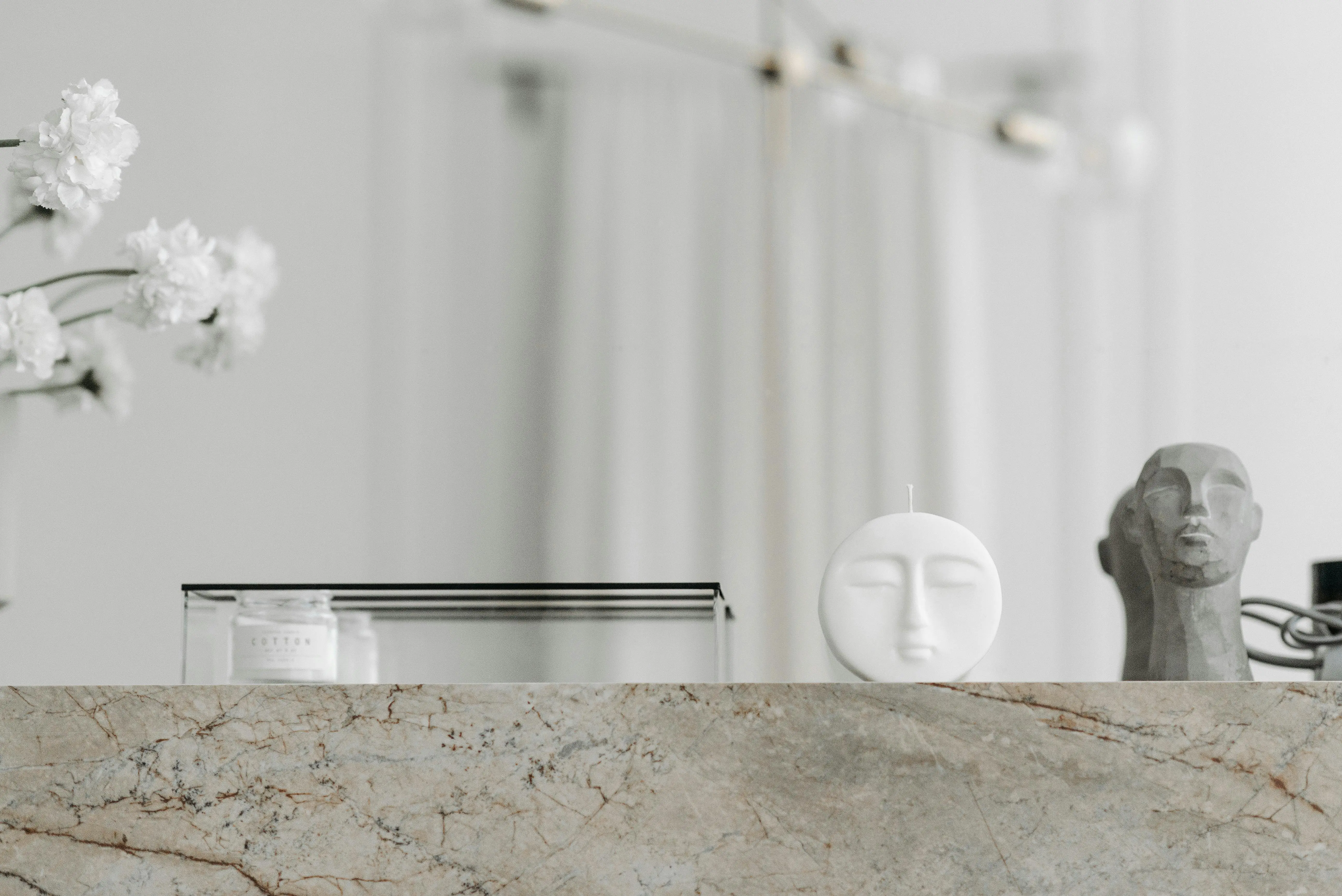 taper candle holders Modern minimalist arrangement with sculptures and a candle on a marble surface, exuding elegance.