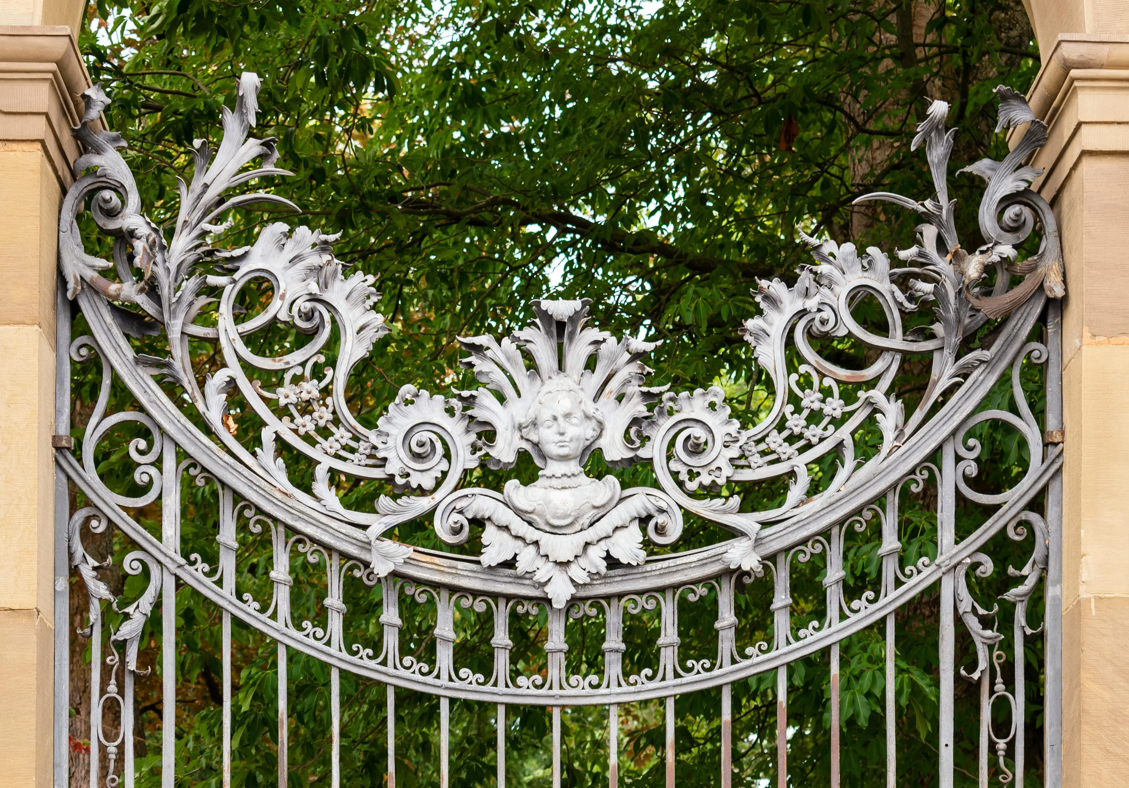 wrought iron patio furniture An intricately designed ornamental iron gate at the Würzburg Residence with lush foliage in the background.