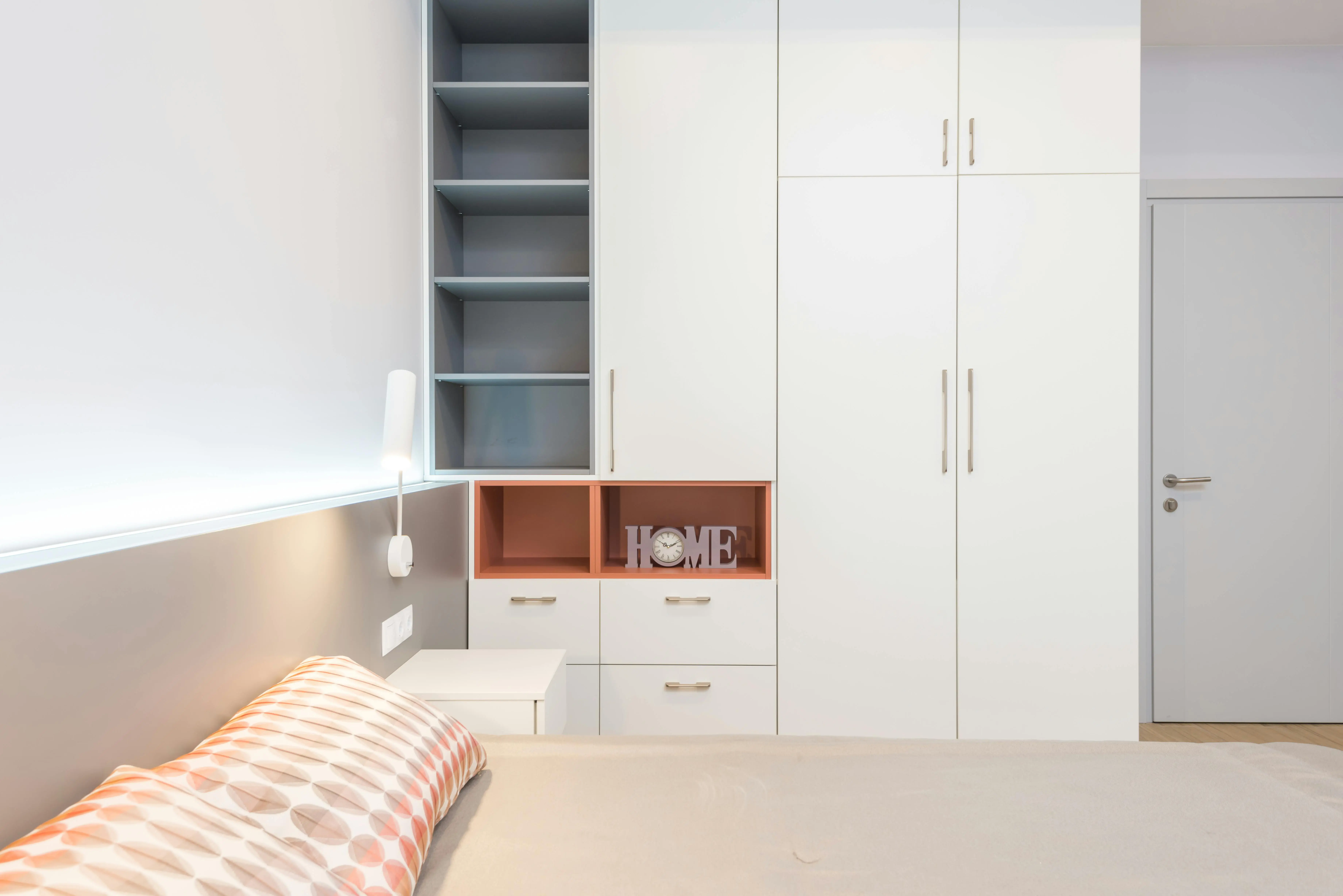 full size bed with storage White wardrobe placed near comfortable bed with cushions and bedside table in modern apartment