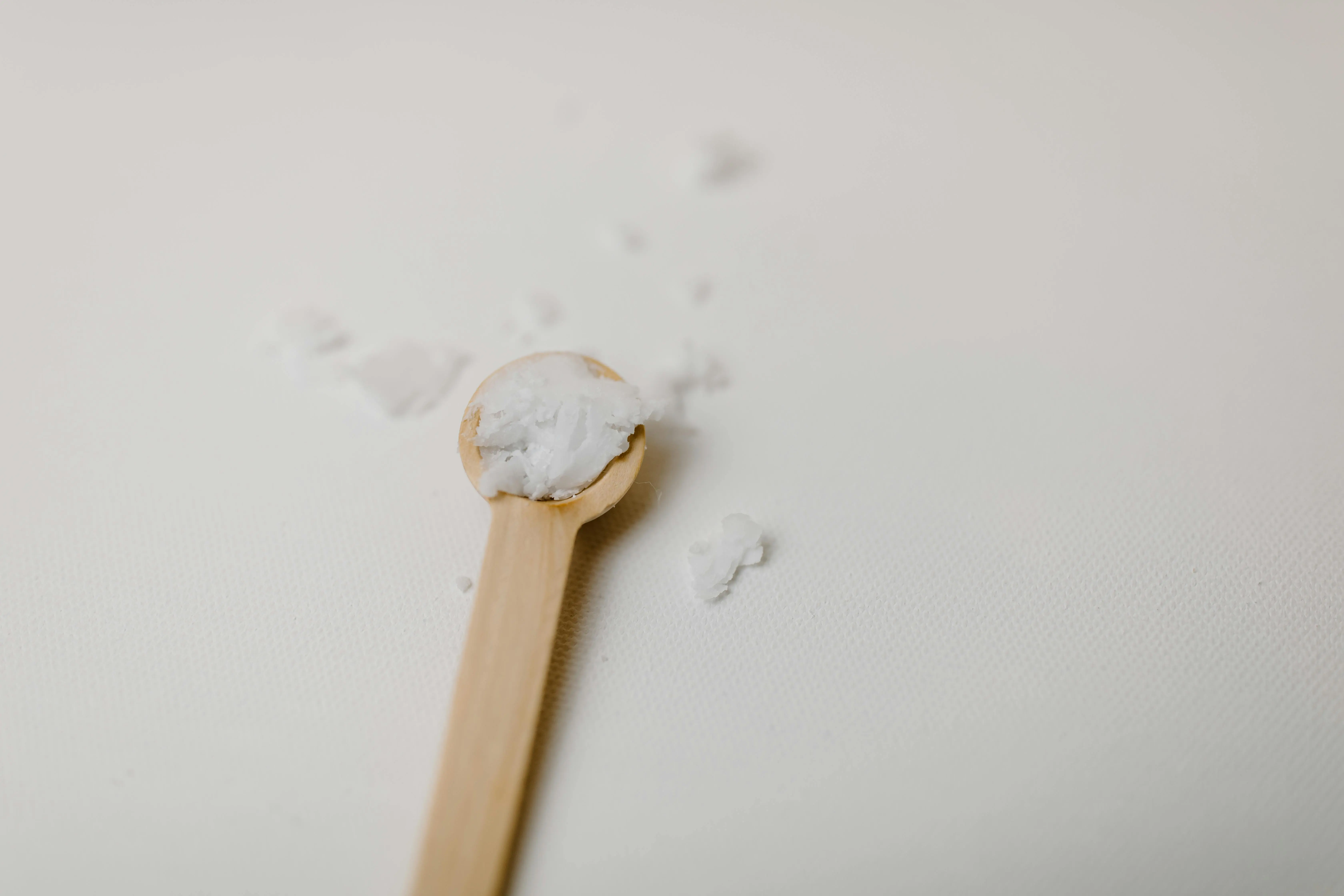 homemade laundry detergent Wooden spoon with scattered white bath salt on a textured surface, minimalist style.