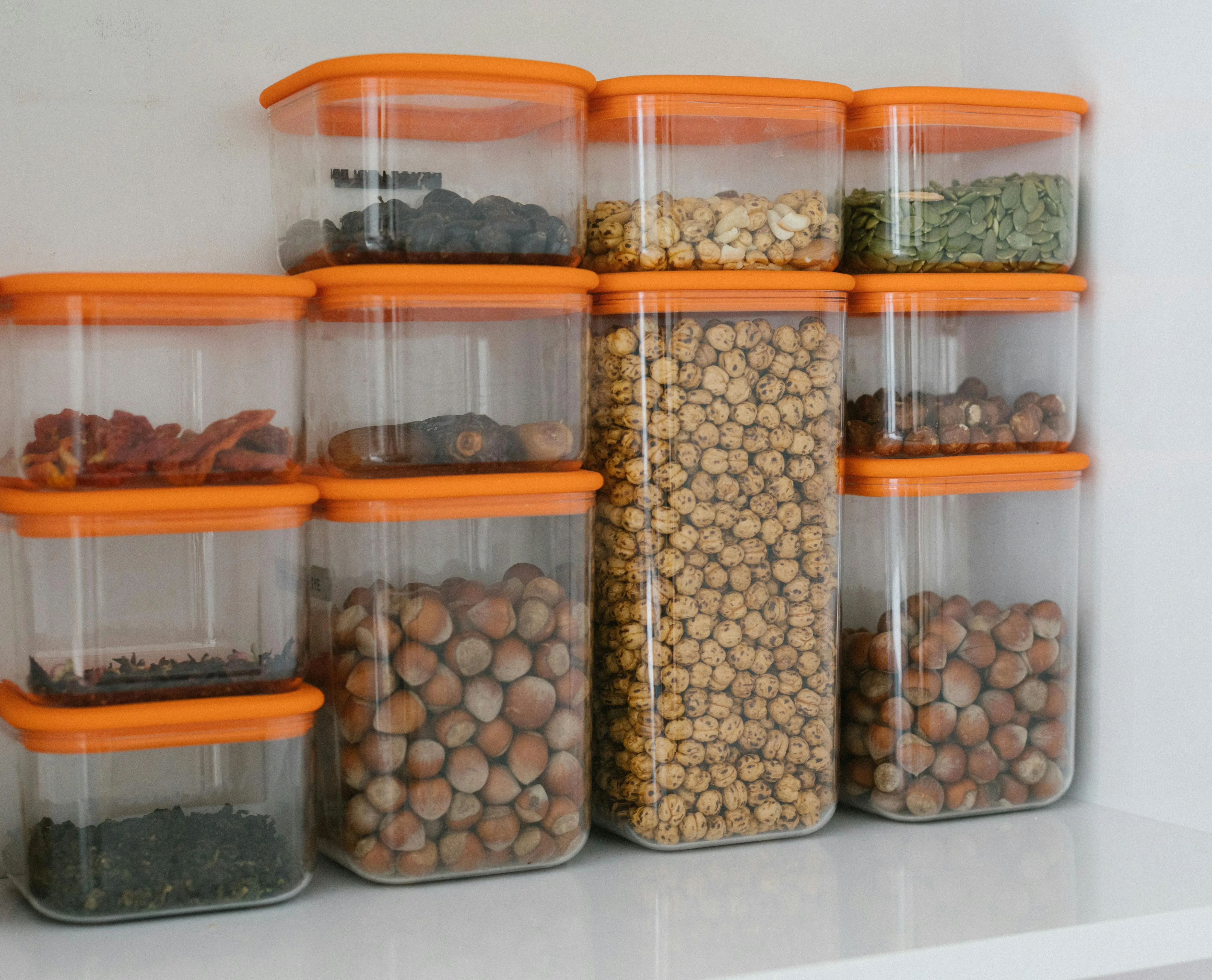 wire closet shelving Various nuts and grains stored in transparent plastic containers with orange lids, organized neatly.