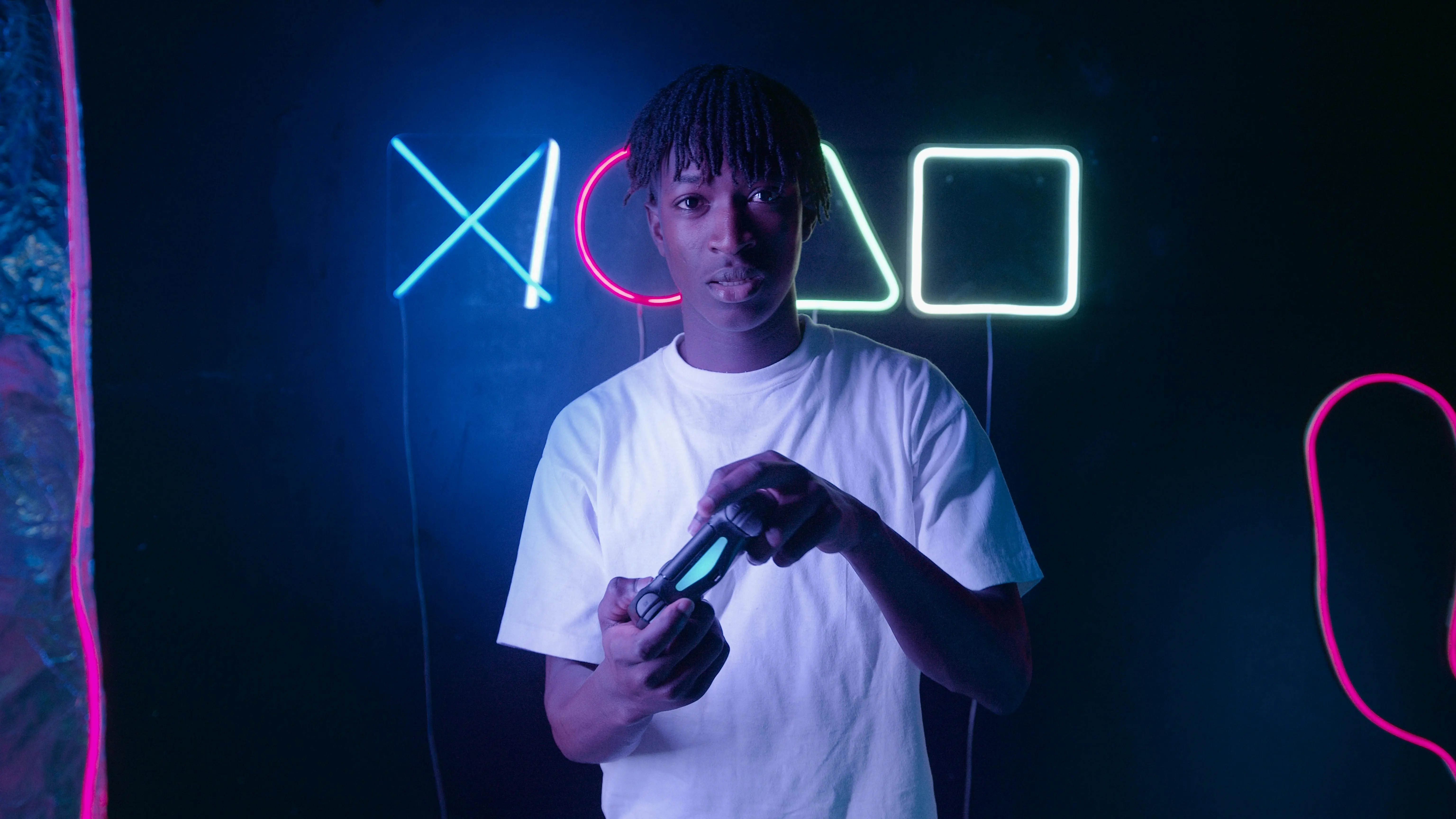 outdoor led strip lights Young man with a game controller against a neon backdrop, showcasing gaming symbols. Futuristic and vibrant atmosphere.