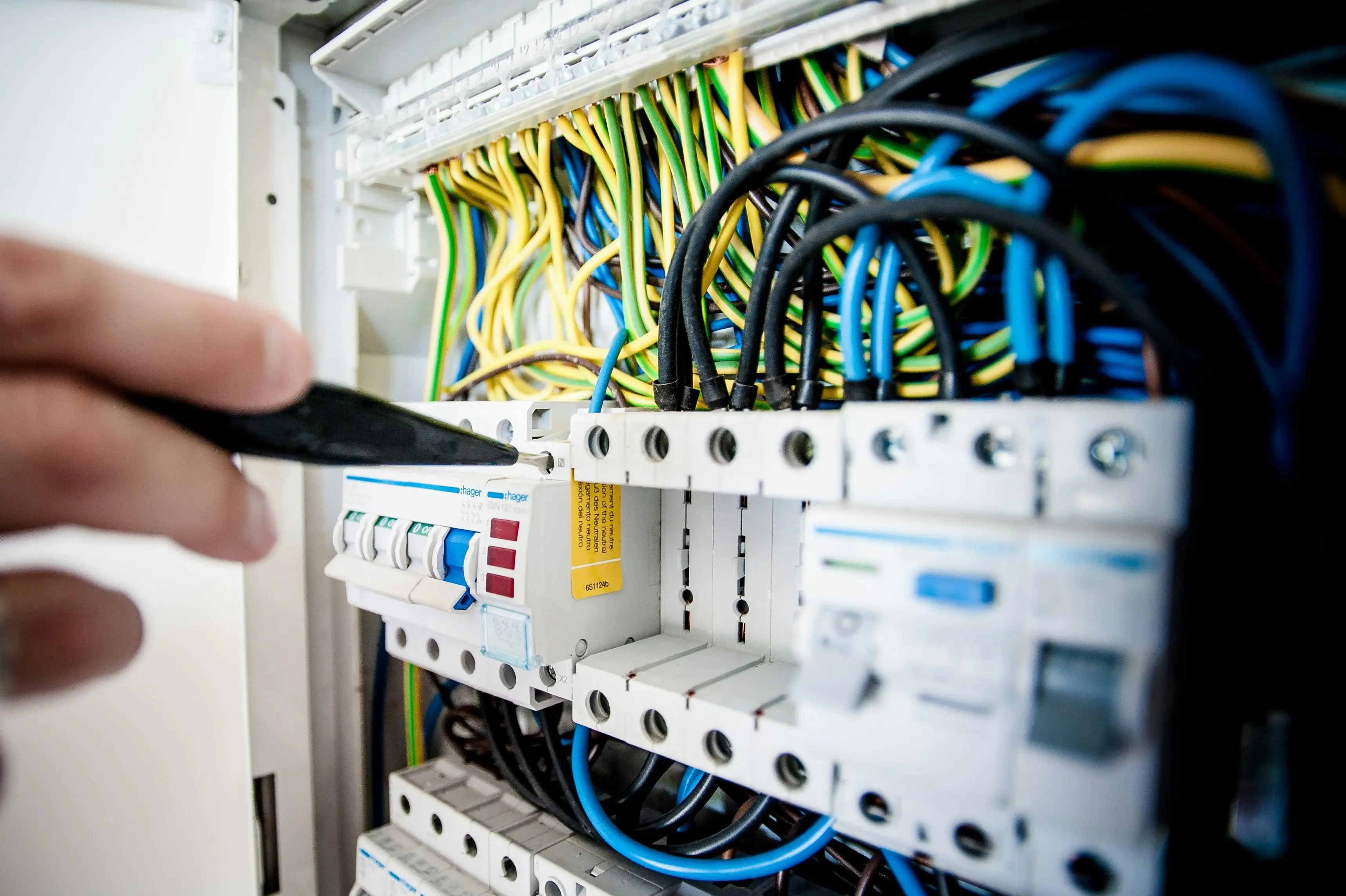ceiling insulation Hand of electrician working on a circuit breaker panel with colorful wires, ensuring safe electrical connections.