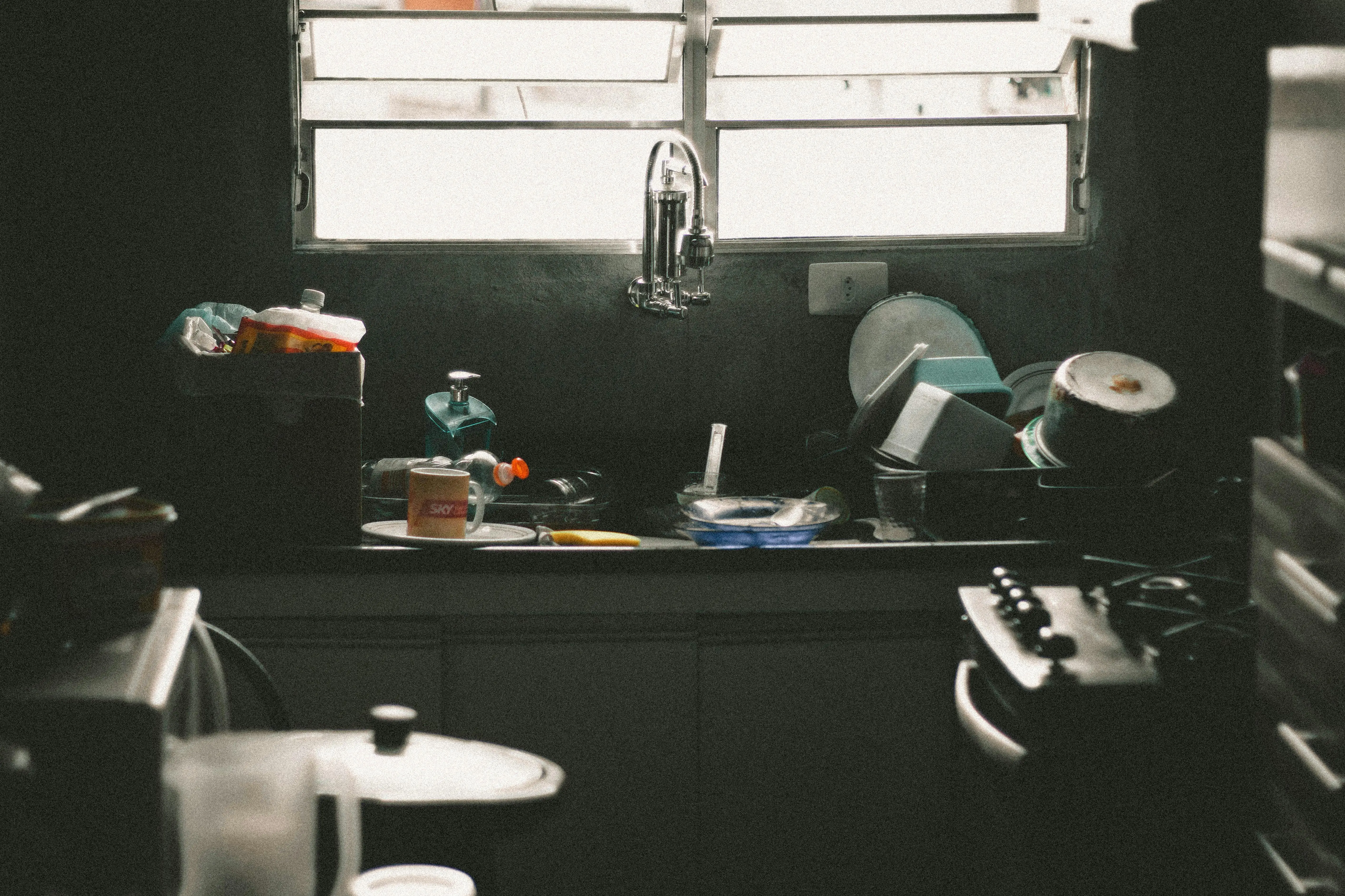 bathroom vanity double sink A cluttered kitchen sink filled with dirty dishes and utensils near a window, creating a messy home interior scene.