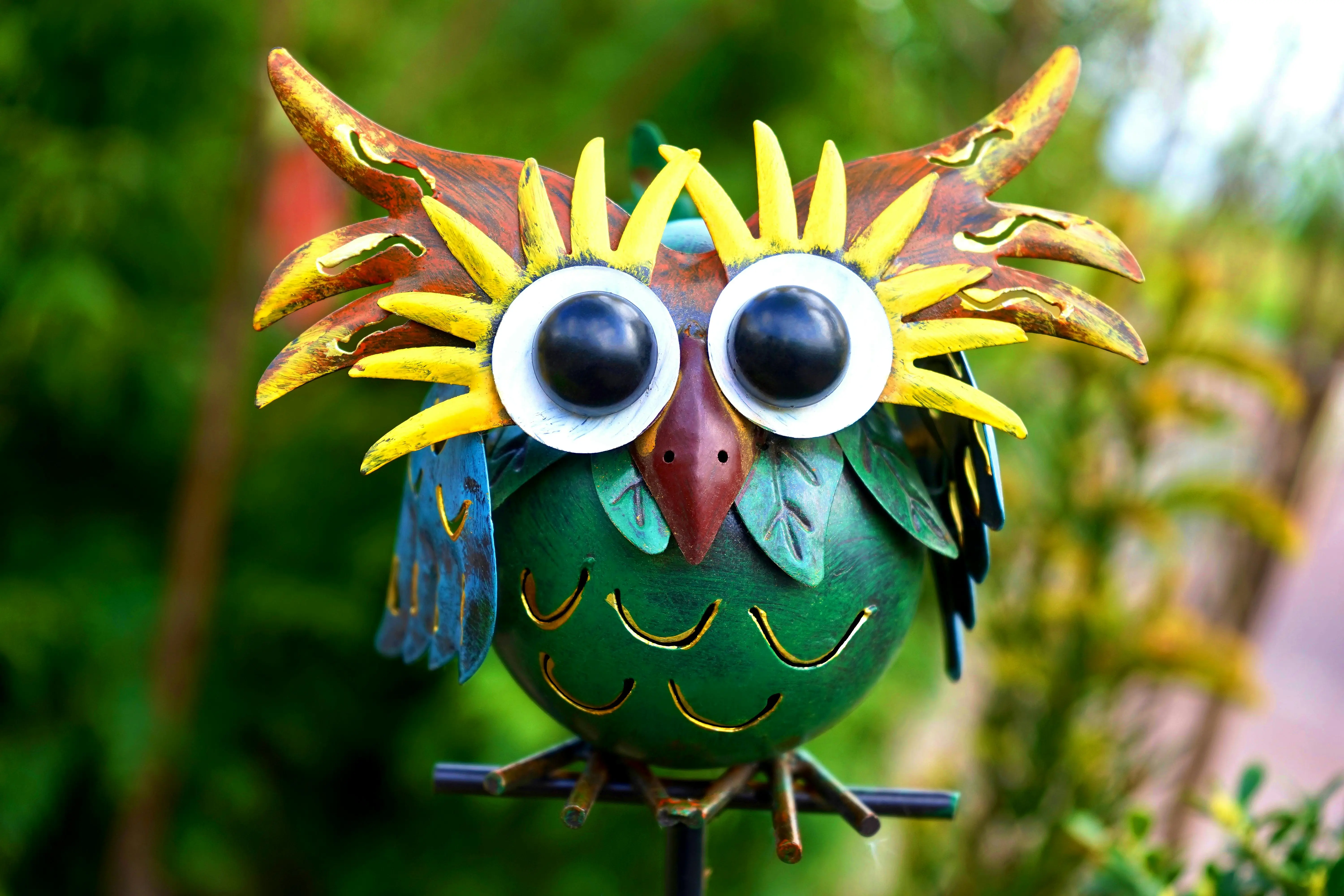 outdoor metal wall art Vibrant metal owl sculpture with exaggerated features in a garden. Perfect decor inspiration.
