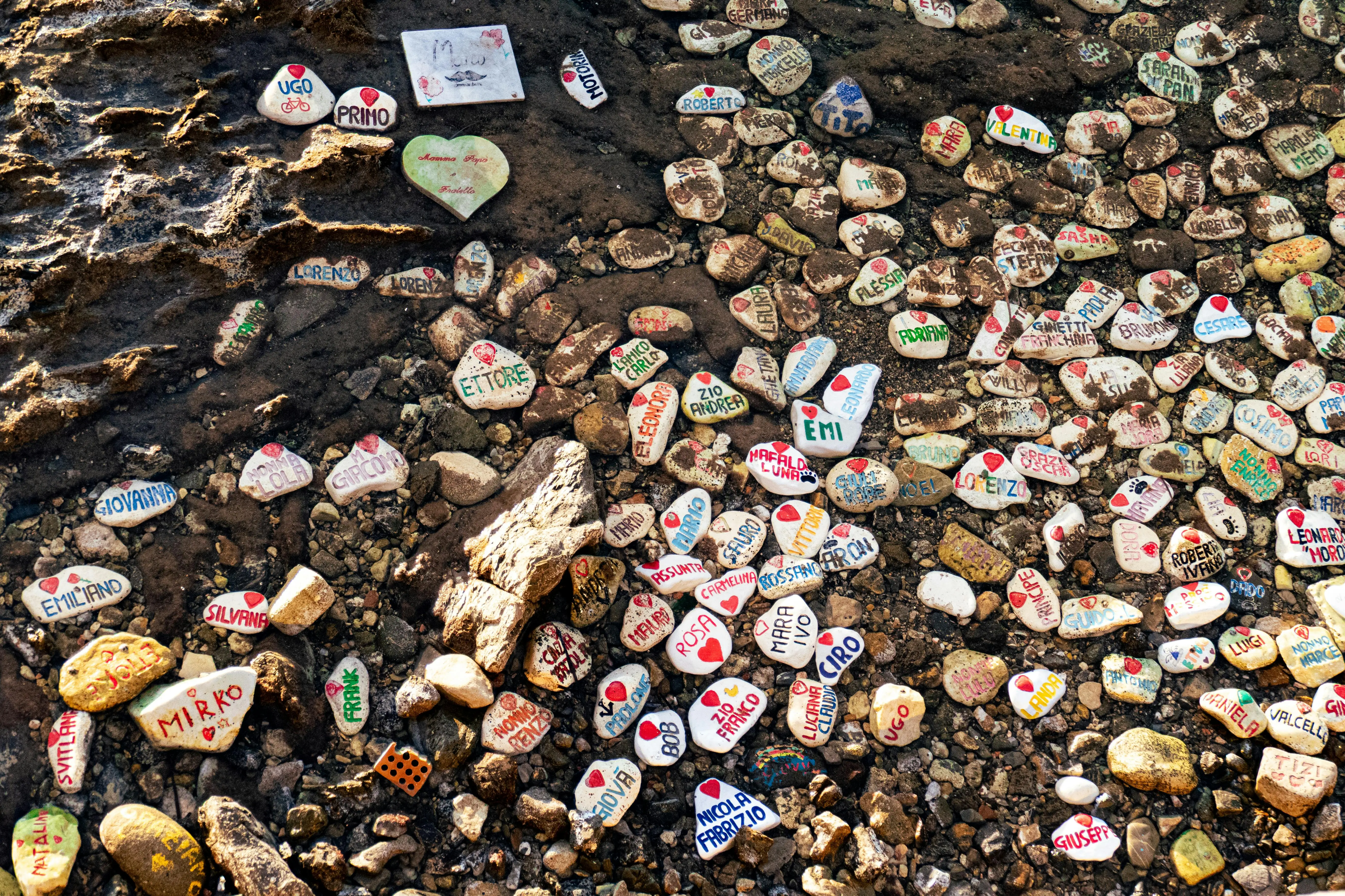 spring crafts A collection of painted stones with names on a beach in Italy, vibrant and intriguing.
