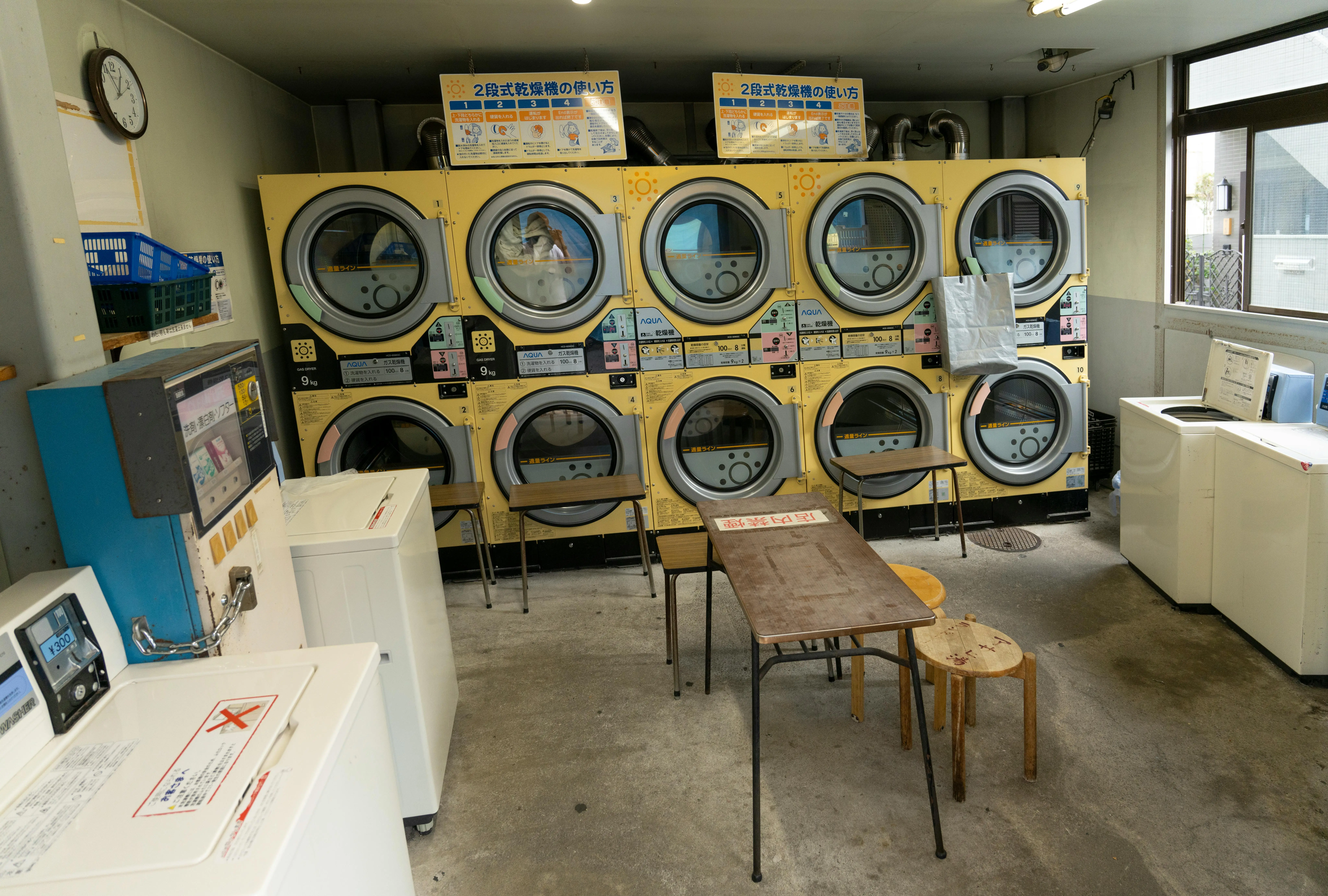 commercial washing machine A compact laundromat in Tokyo with washing machines, dryers, and seating, showcasing urban lifestyle.