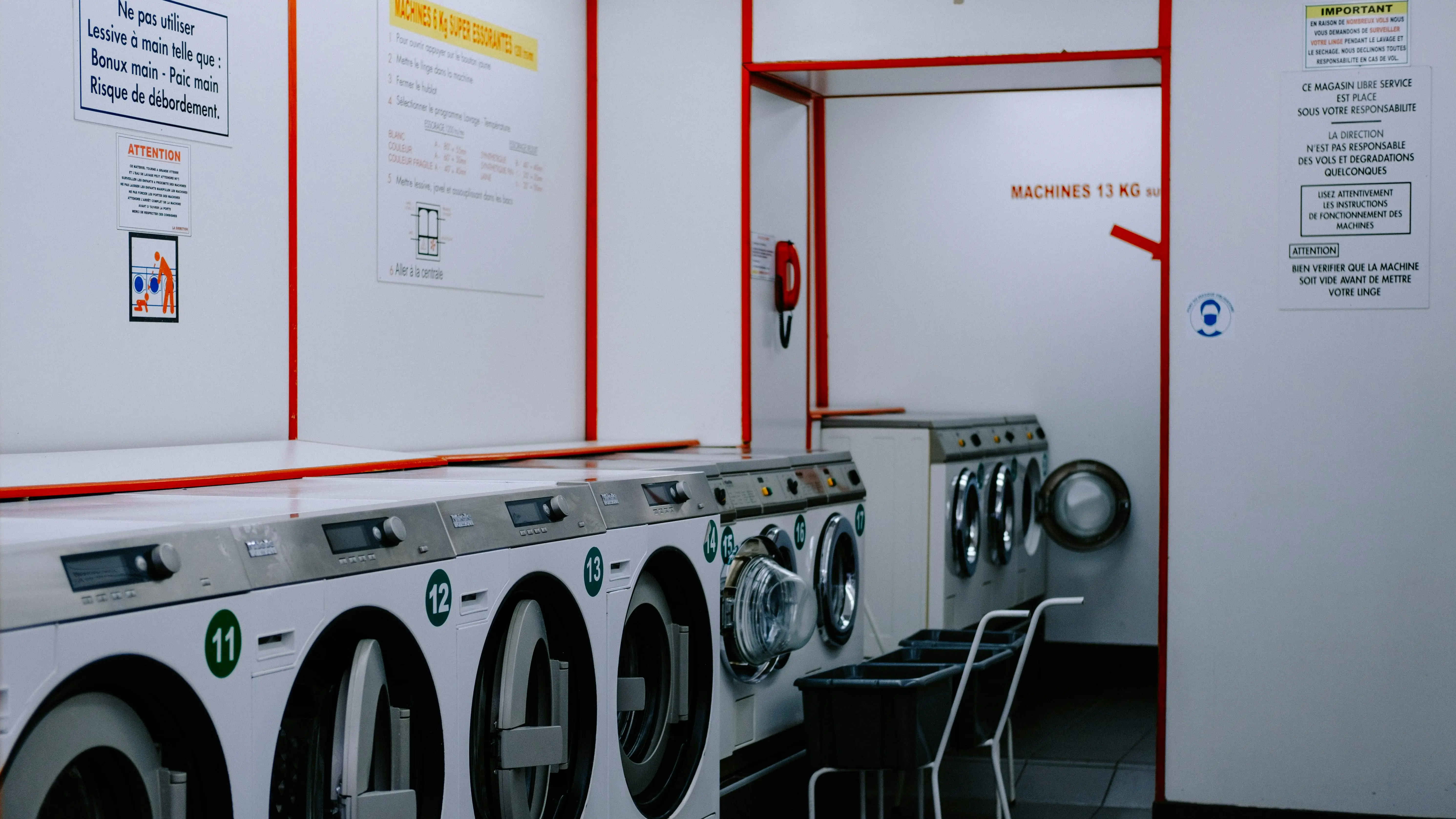 commercial washing machine Inside a laundromat with washing machines lined up against the wall.