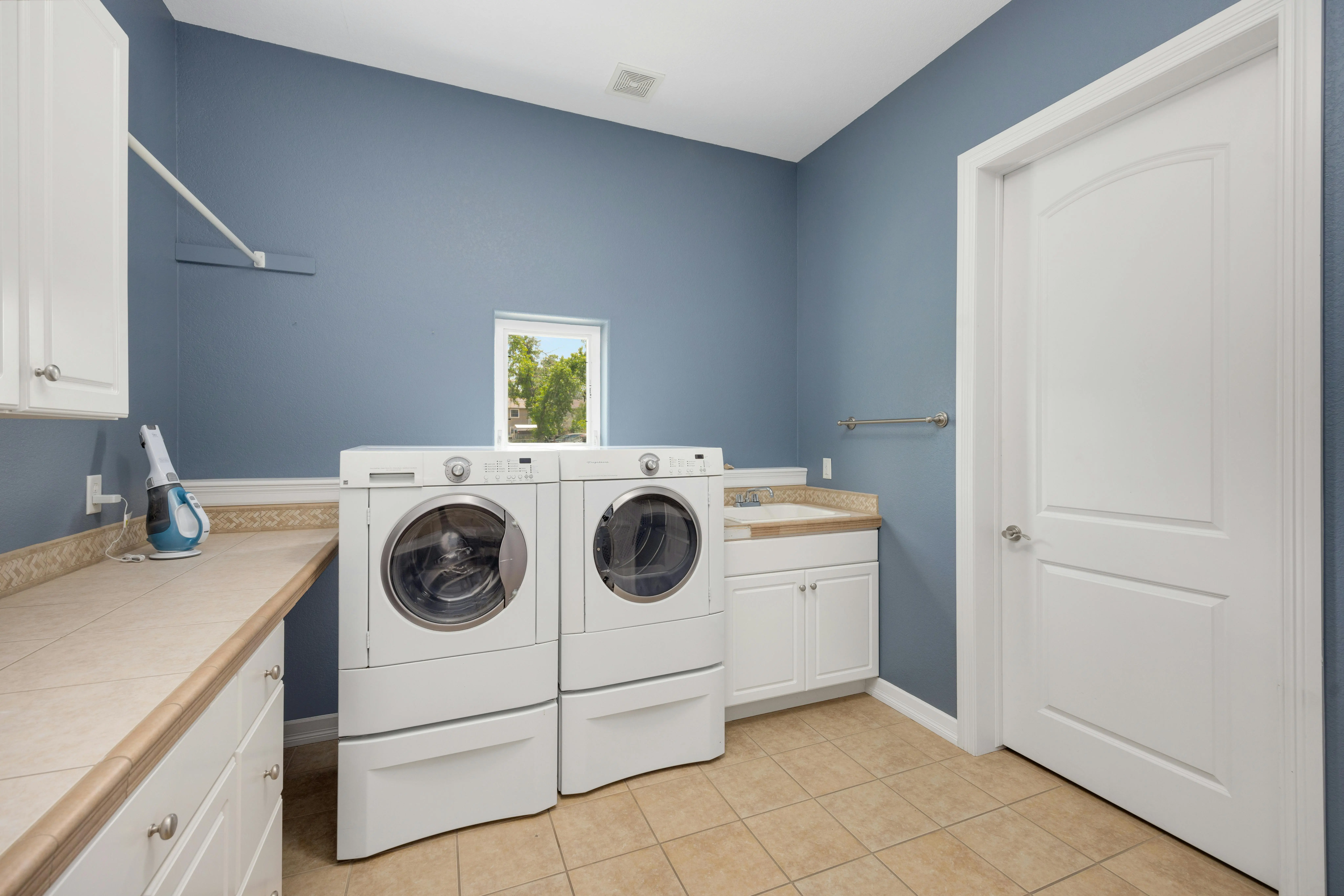 stacked washer dryer dimensions Clean and spacious laundry room featuring modern washing appliances and storage cabinets.