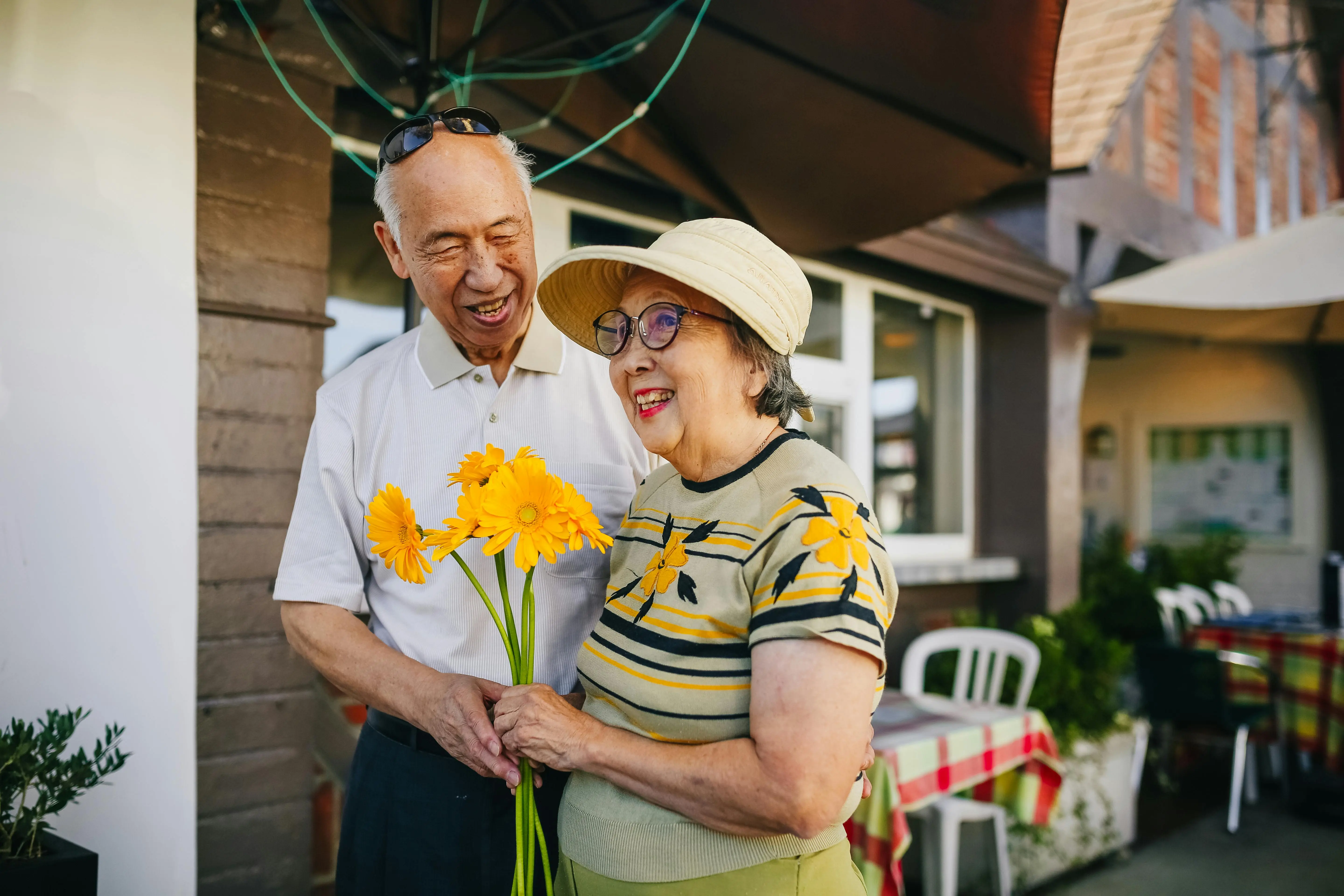 lily bouquet Happy senior couple enjoying a moment with yellow flowers outside a restaurant.