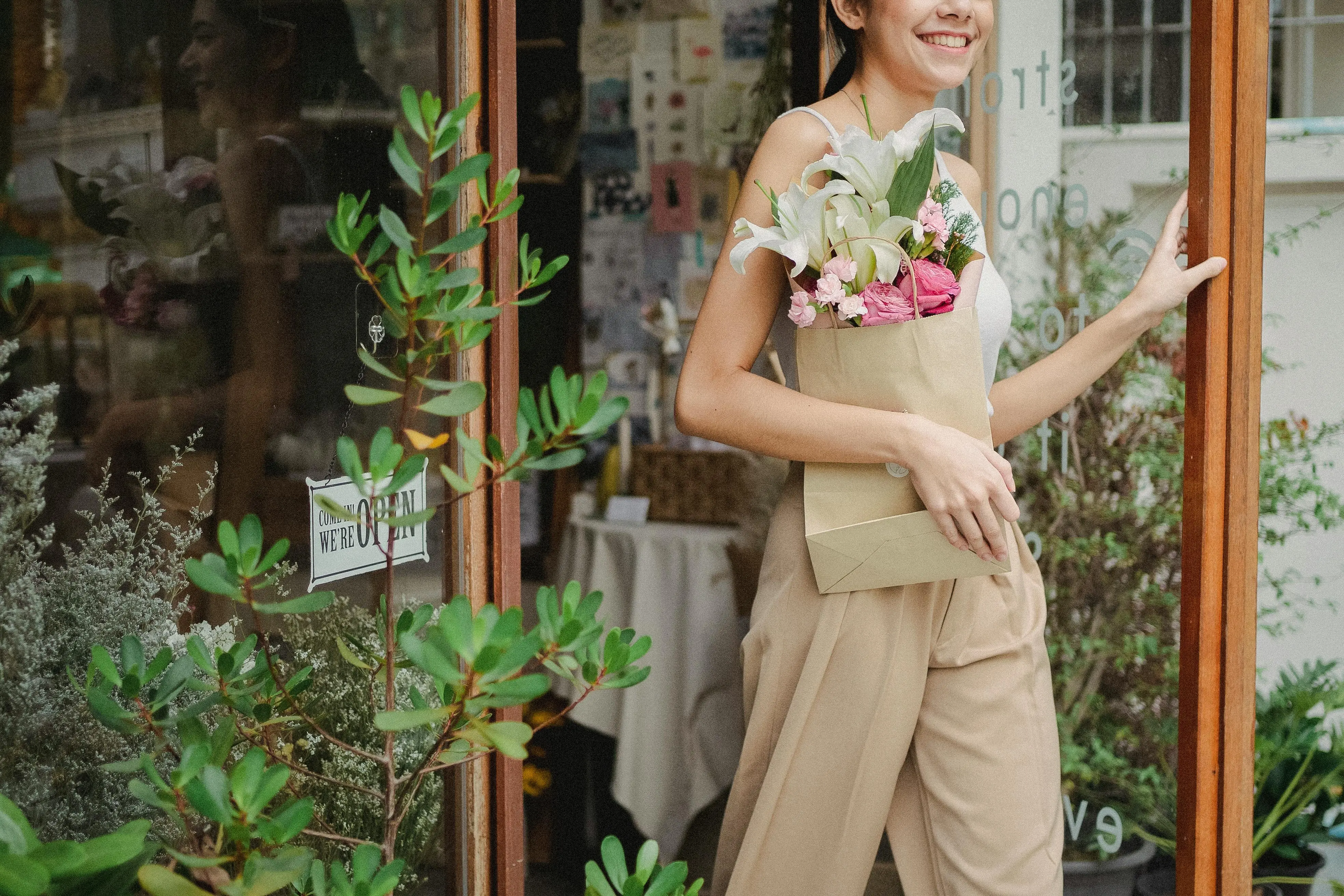 lily bouquet Smiling woman carrying floral bouquet outside a charming flower shop.