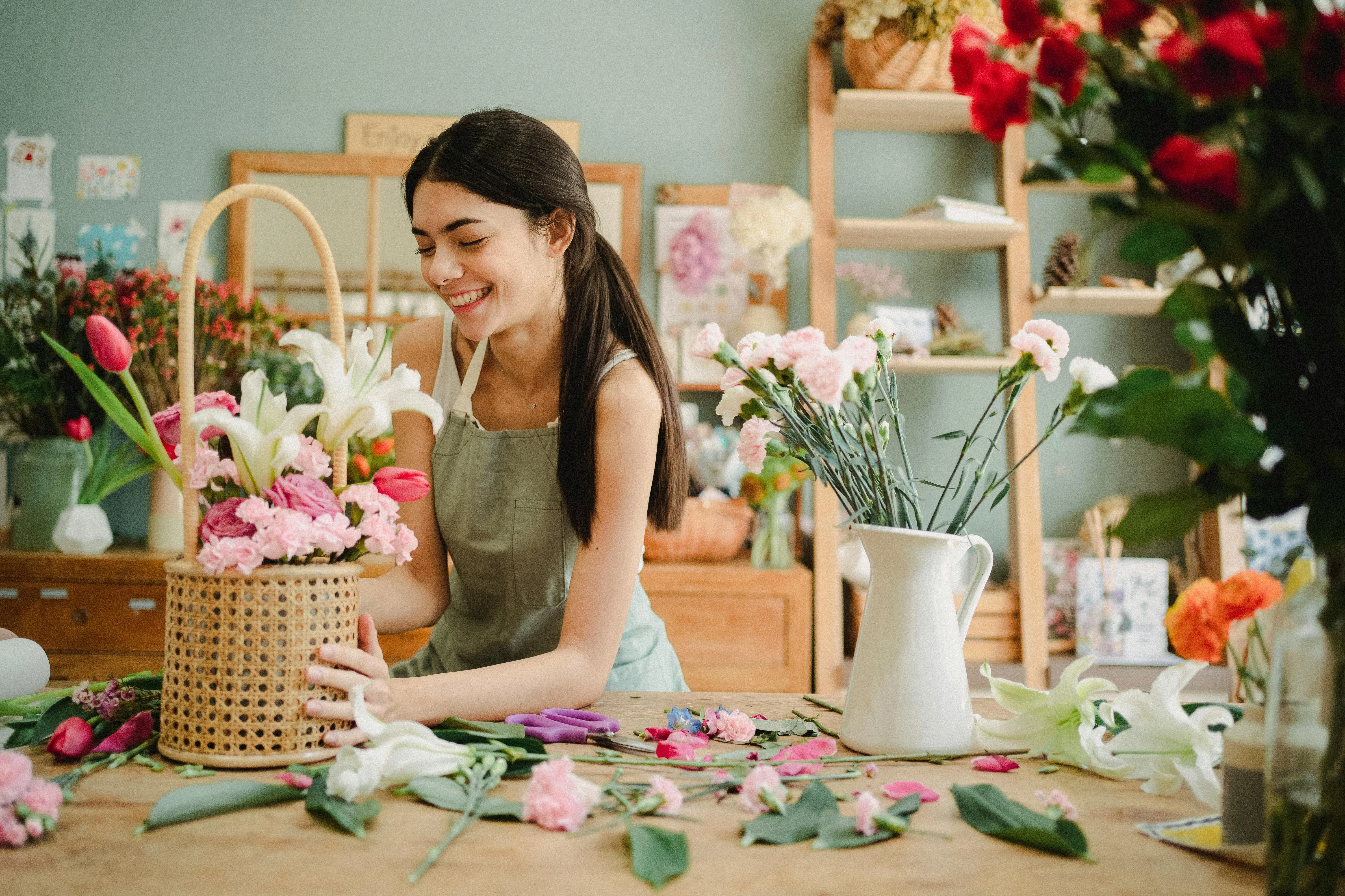lily bouquet Smiling female florist arranging flower bouquet in a studio, surrounded by vibrant florals.