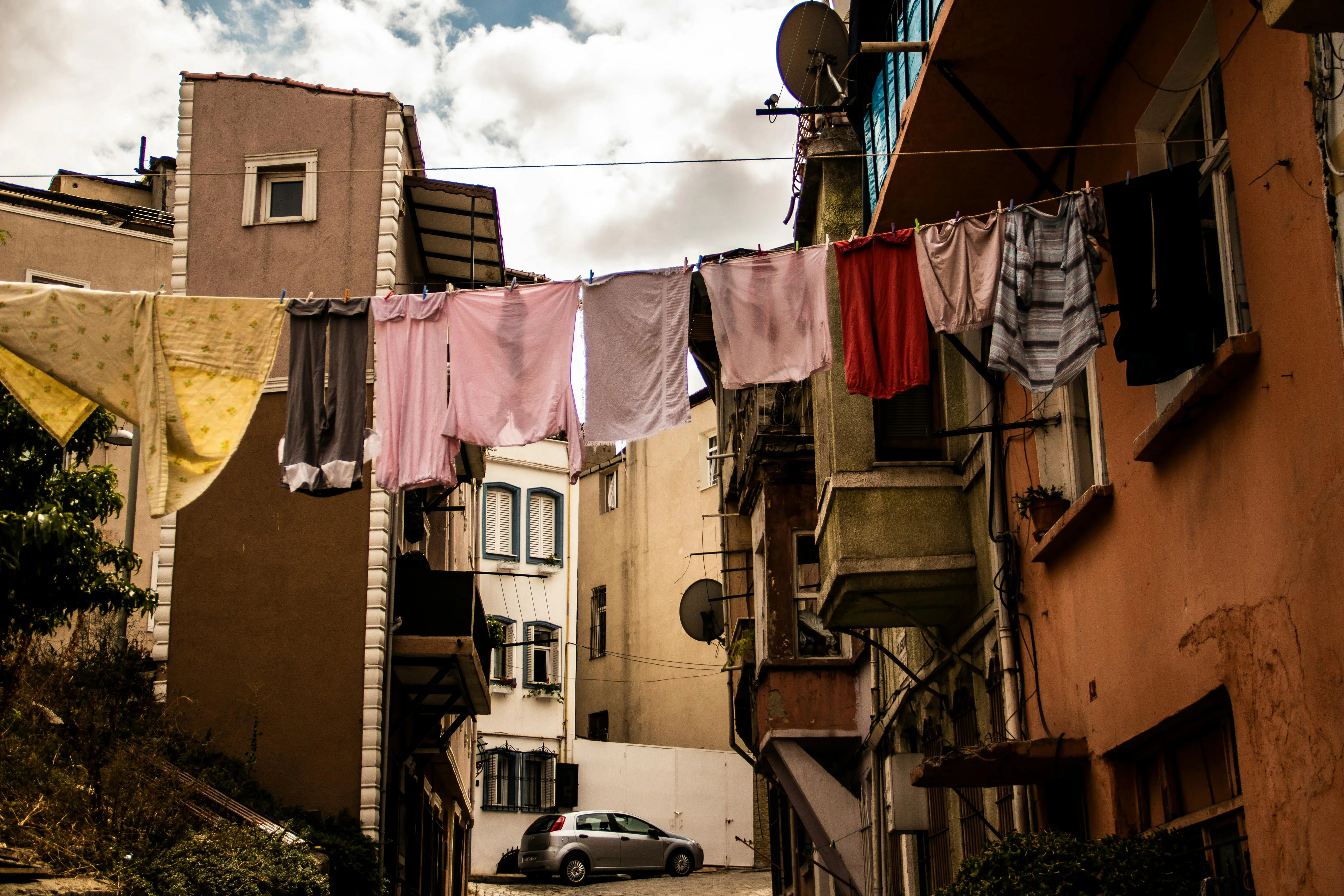 how to get mildew smell out of clothes Charming urban scene of clothes hanging on a line between buildings under a cloudy sky.