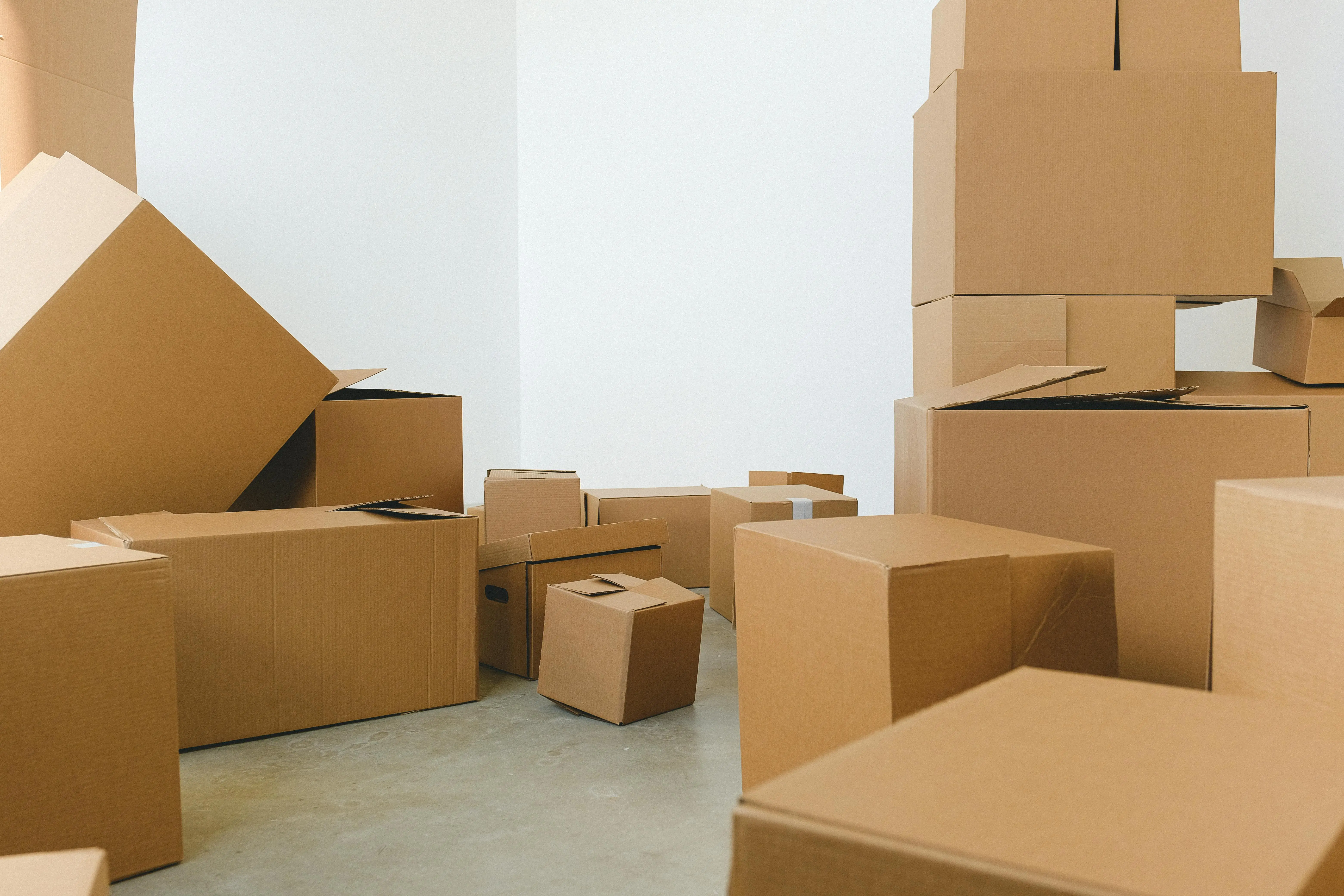 24 hour storage Stack of carton boxes of various shapes and sizes scattered in floor near white walls during relocation
