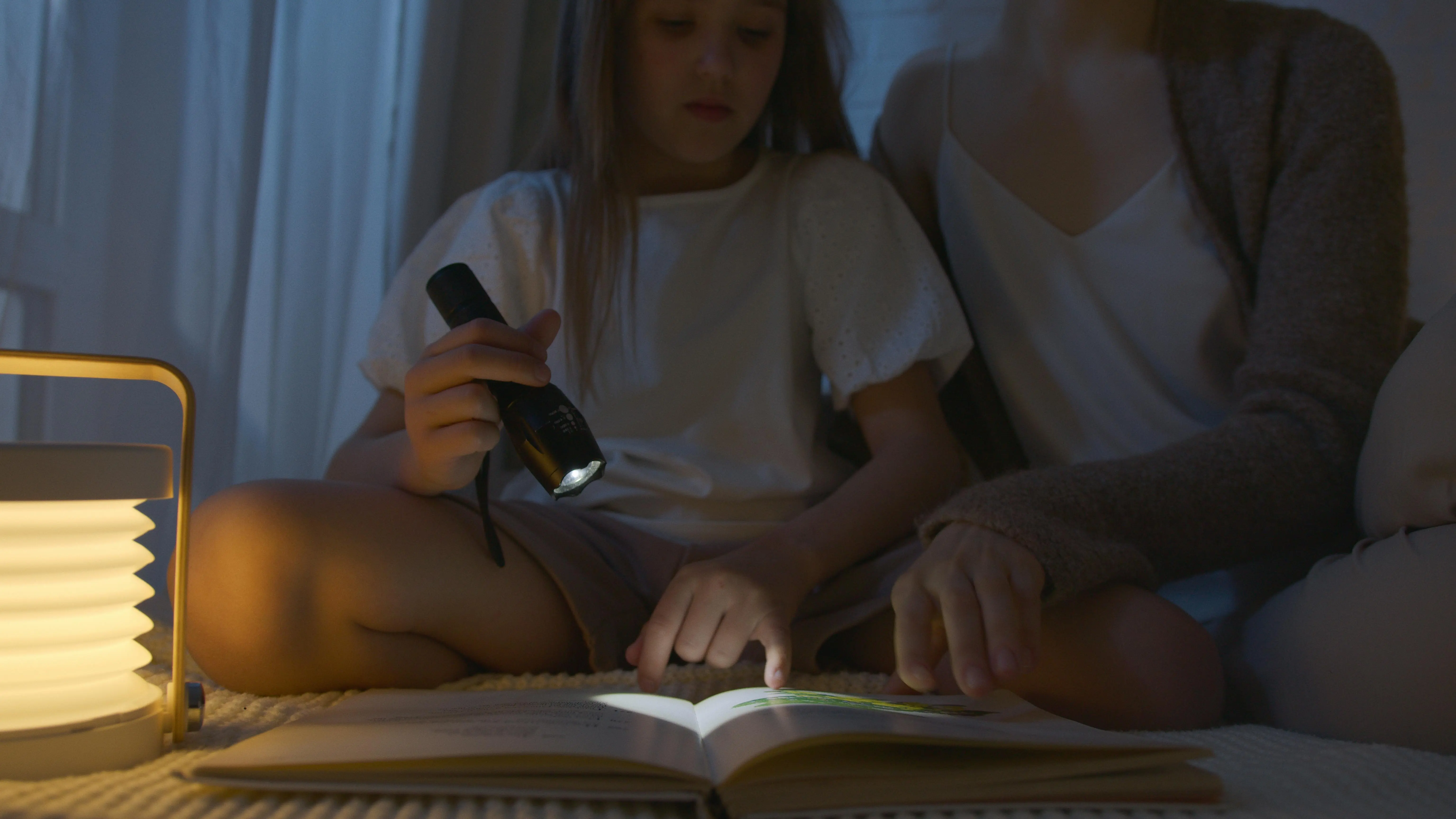 mini lamp A child and adult reading a book at night using a flashlight, creating a cozy atmosphere.