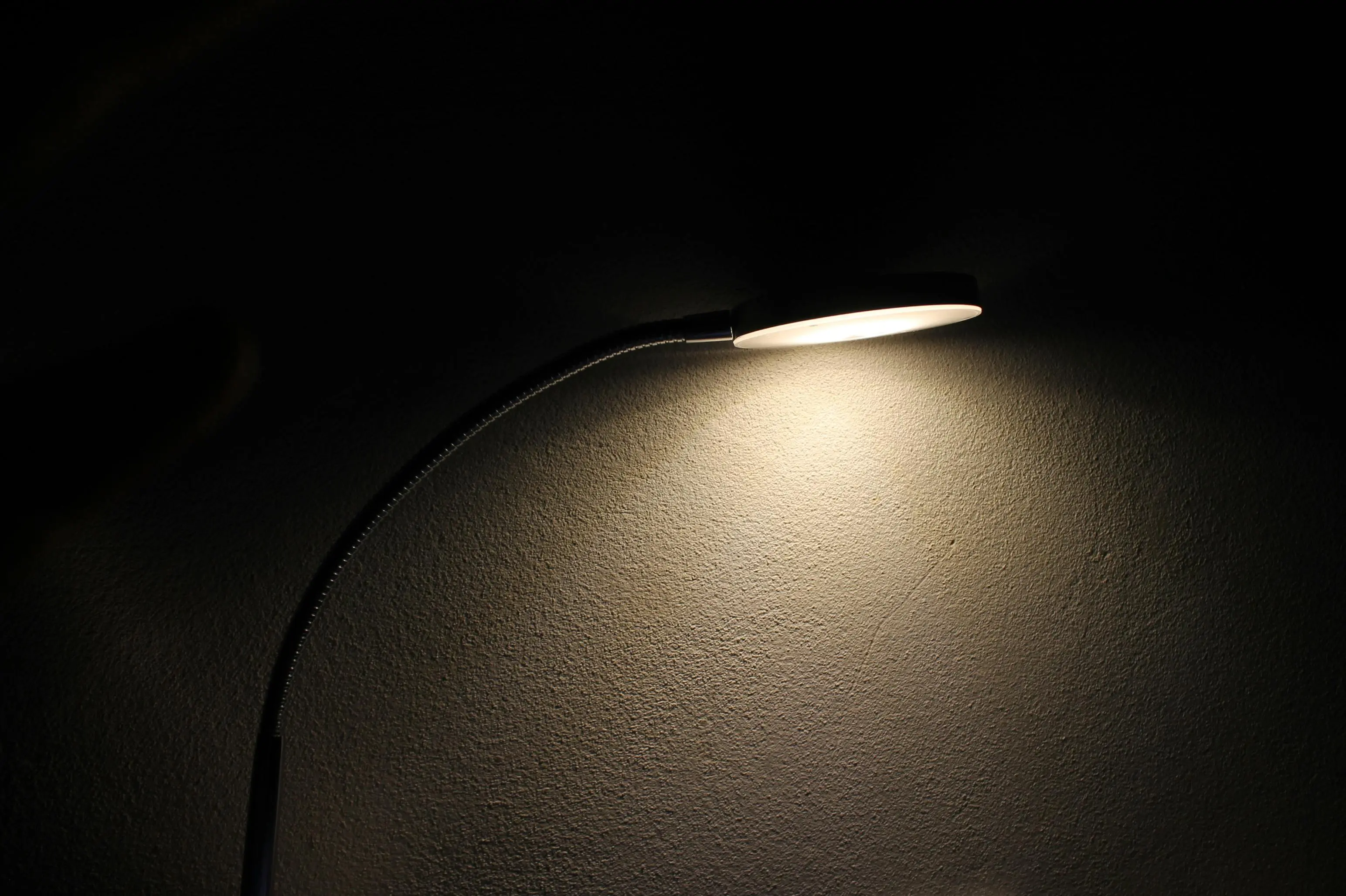 mini lamp A sleek desk lamp casts a soft glow on a textured wall, creating a moody ambiance.