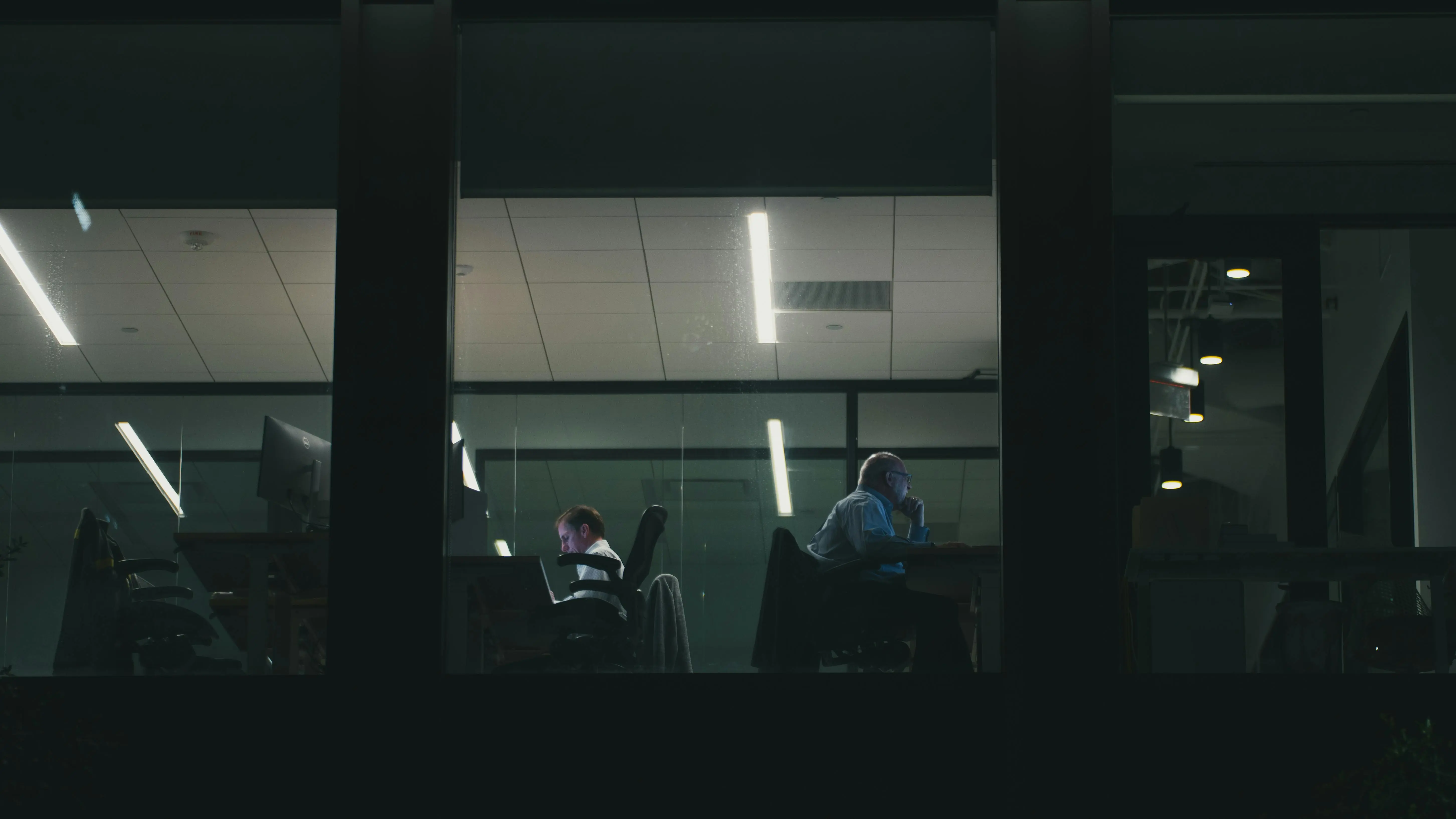 24 hour storage Two people working late in a modern Houston office building, visible through a window.