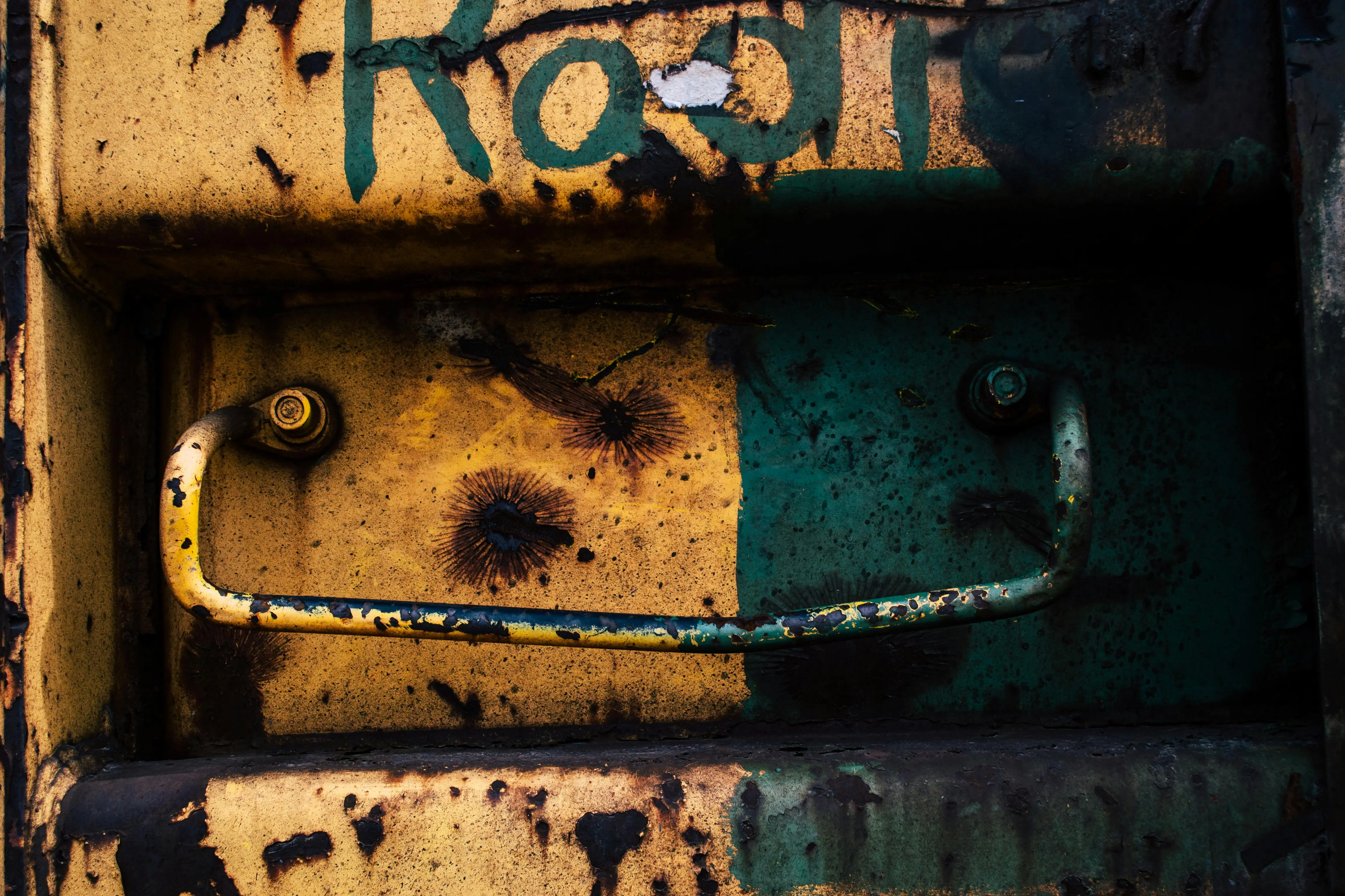 outdoor metal wall art Close-up of a rusty metal door featuring graffiti and a peeling handle, embodying urban decay.