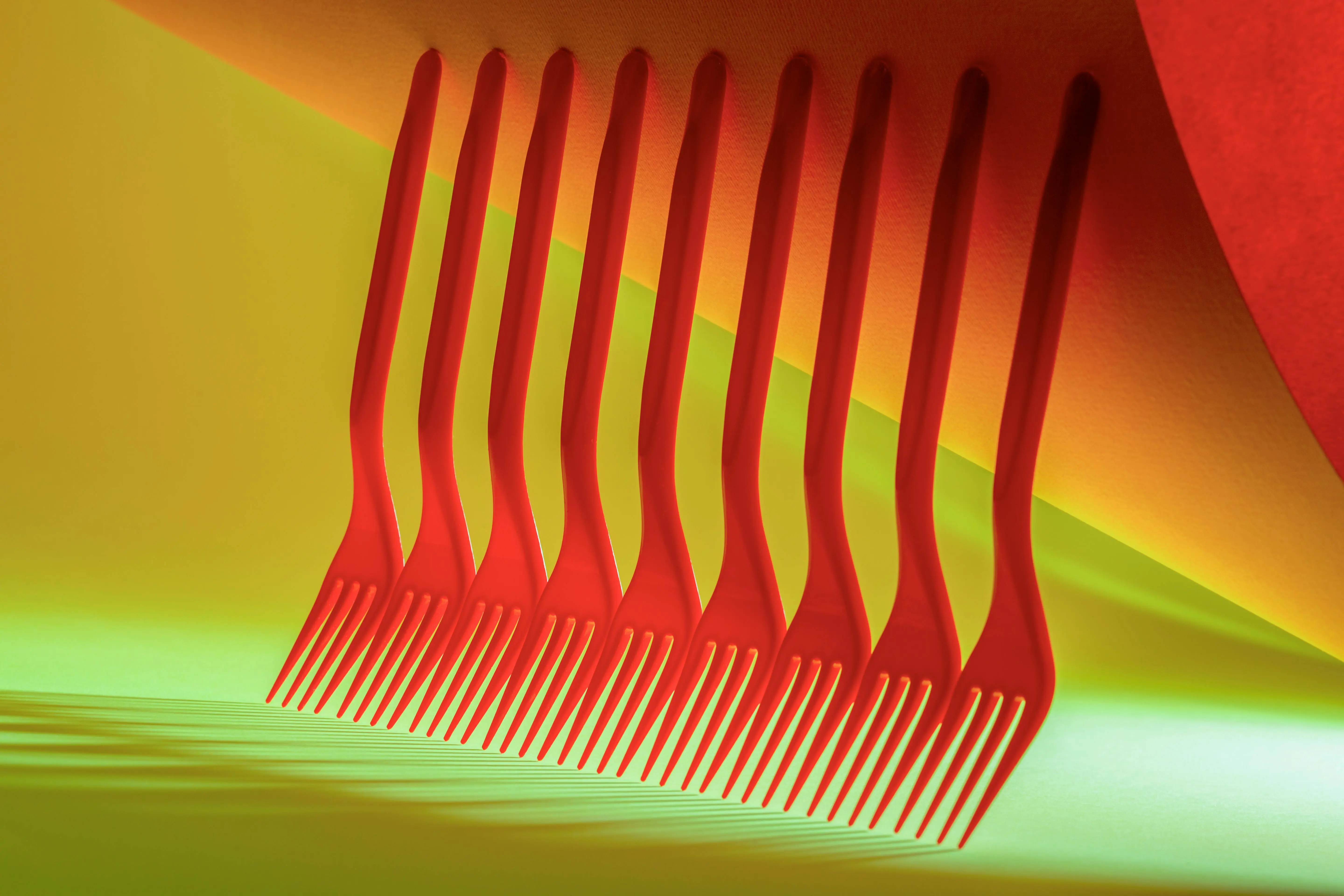 what to paint A creative arrangement of red forks on a vibrant yellow and green background, showcasing abstract art.