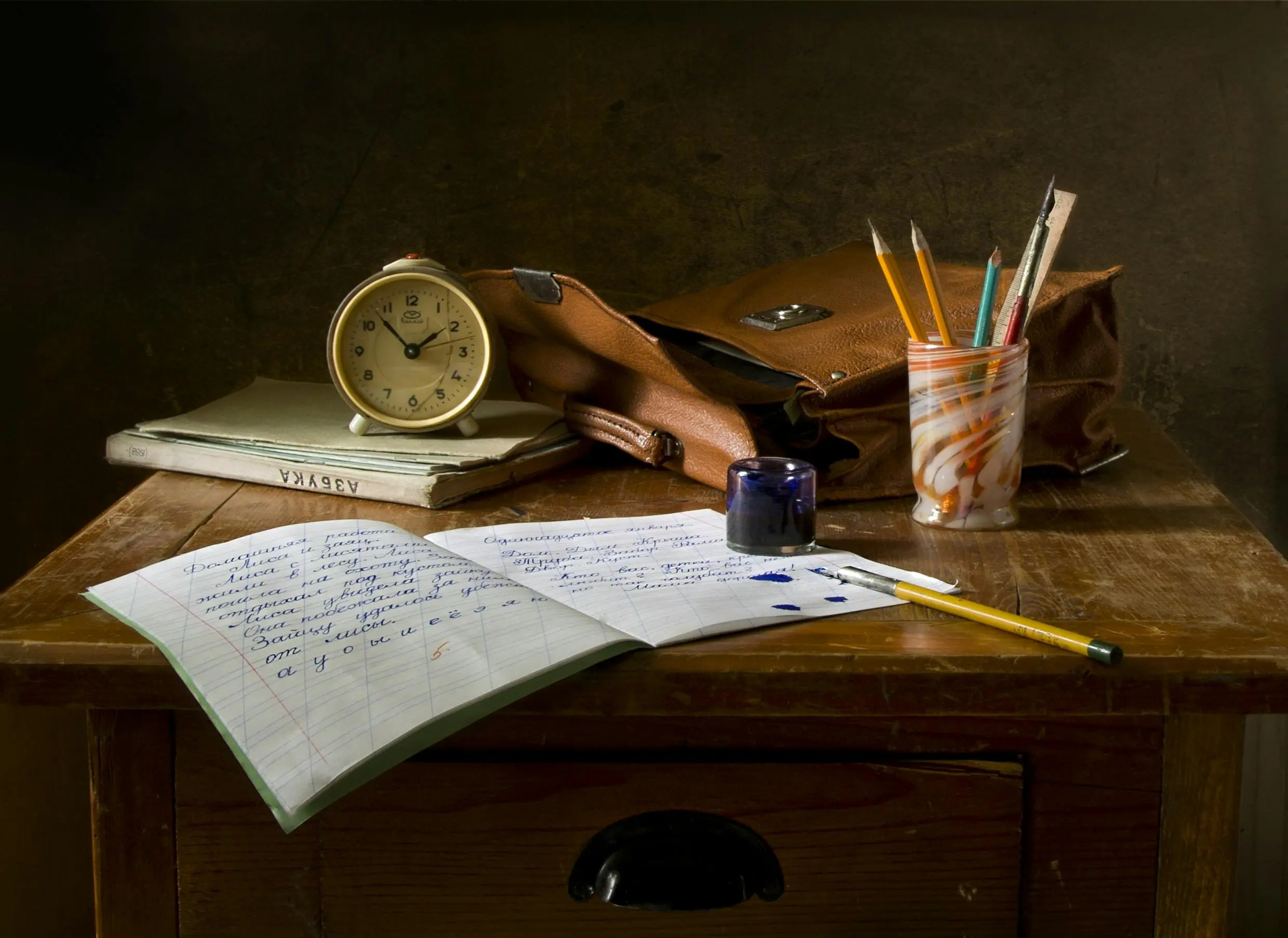 desk bed Classic wooden desk with writing materials, vintage clock, and a leather bag.