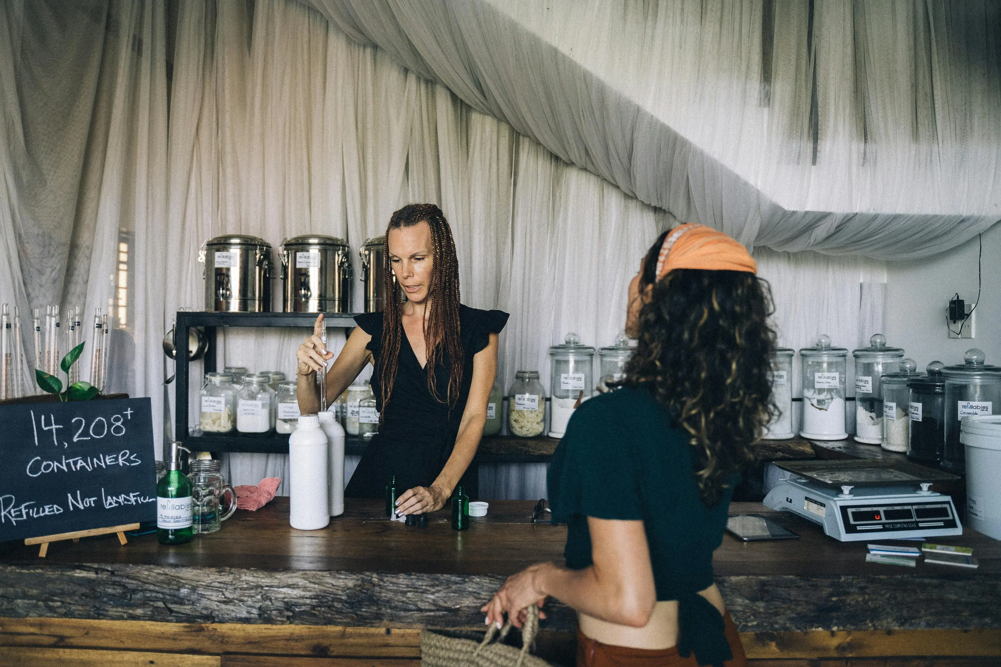 how to make laundry detergent Two women engage at a sustainable refill station with reusable containers.