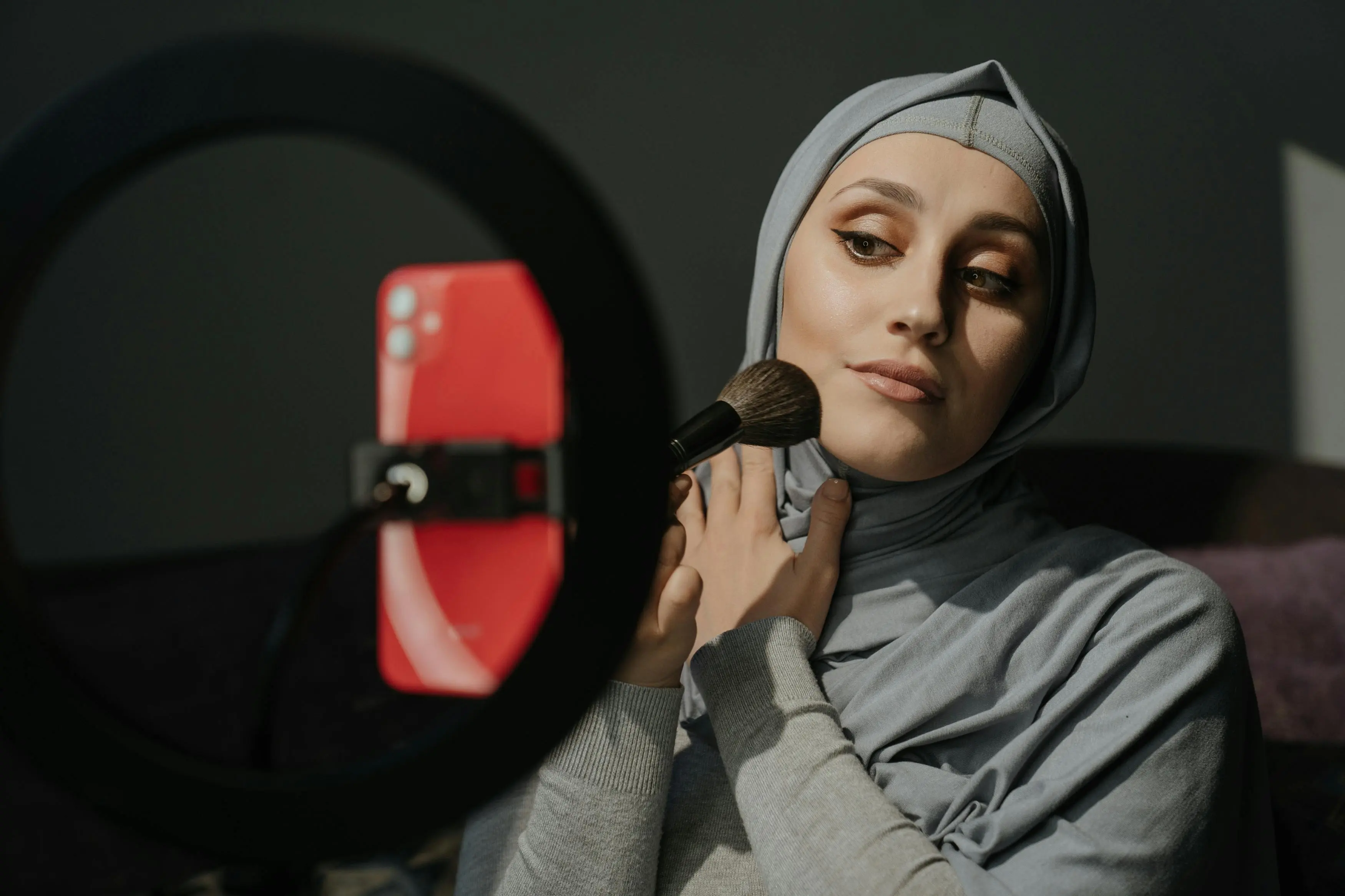 how to remove ink from leather A Muslim woman in a hijab applies makeup for a tutorial indoors.
