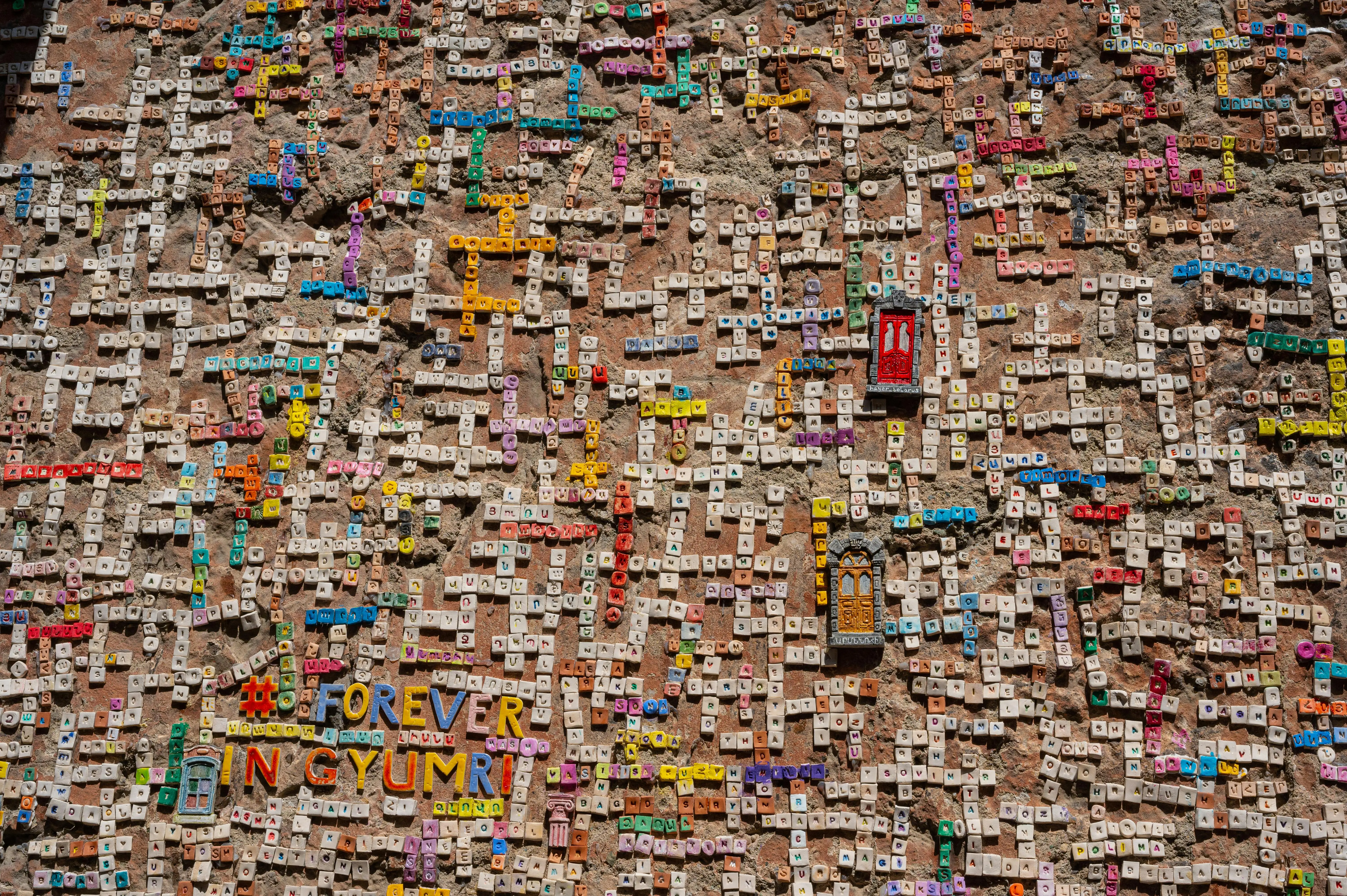 peel and stick stone tile Vibrant tile mosaic on a wall showcasing letters and words in Gyumri, Armenia.