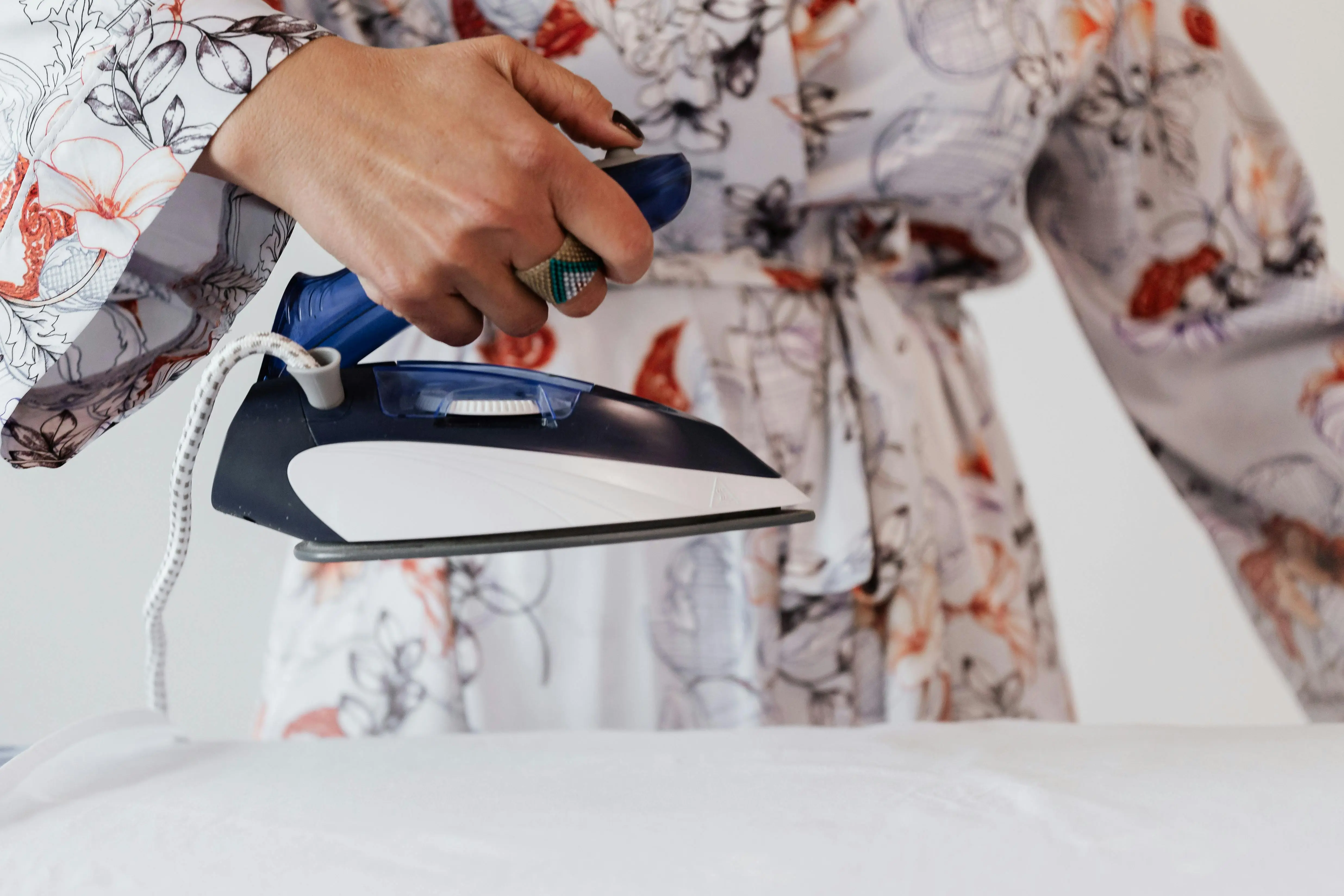 how to wash silk Stylish woman in floral robe ironing at home, showcasing modern elegance and domestic lifestyle.