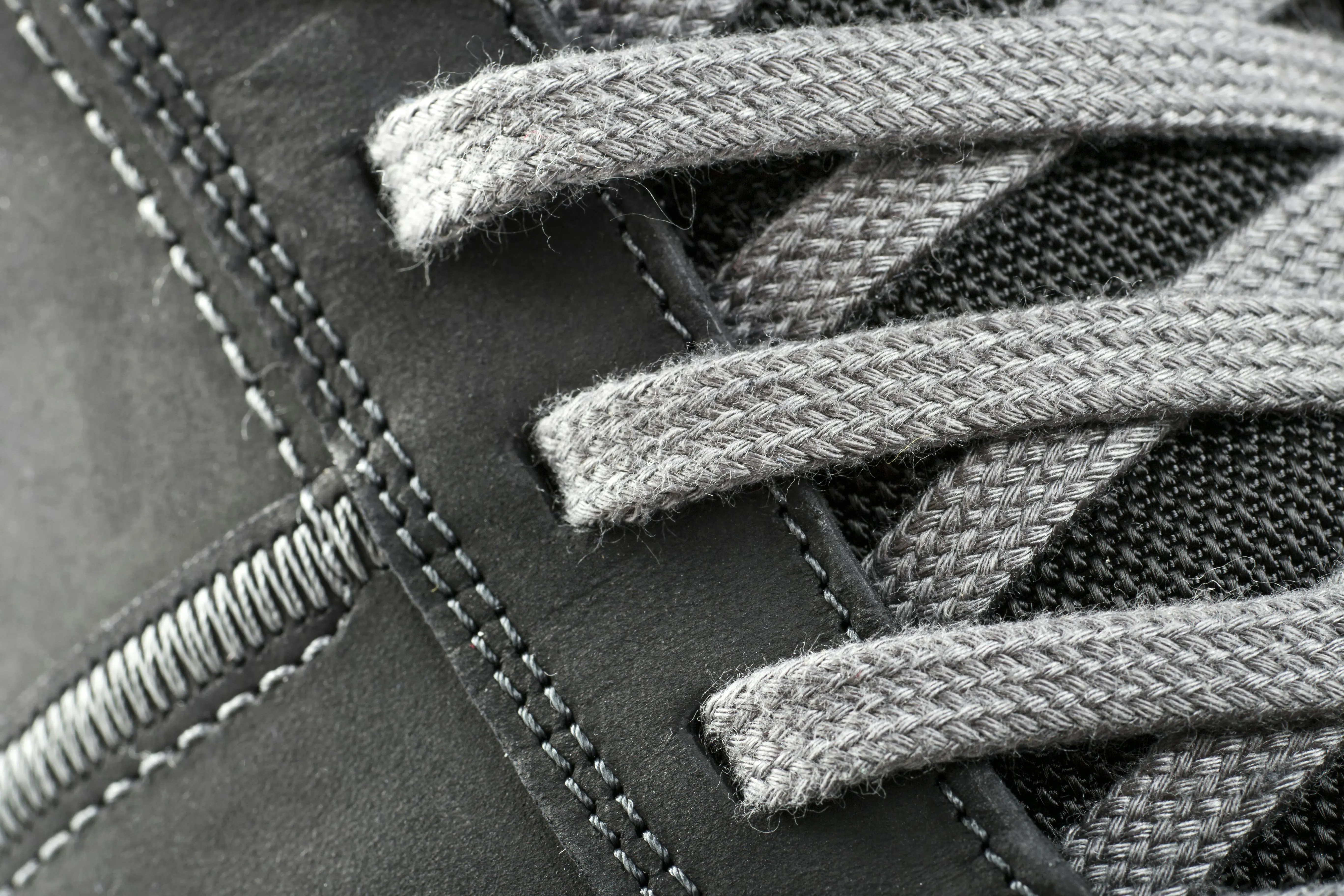 how to remove ink from leather Detailed close-up of a shoe lace intertwined with stitching on a gray sneaker.