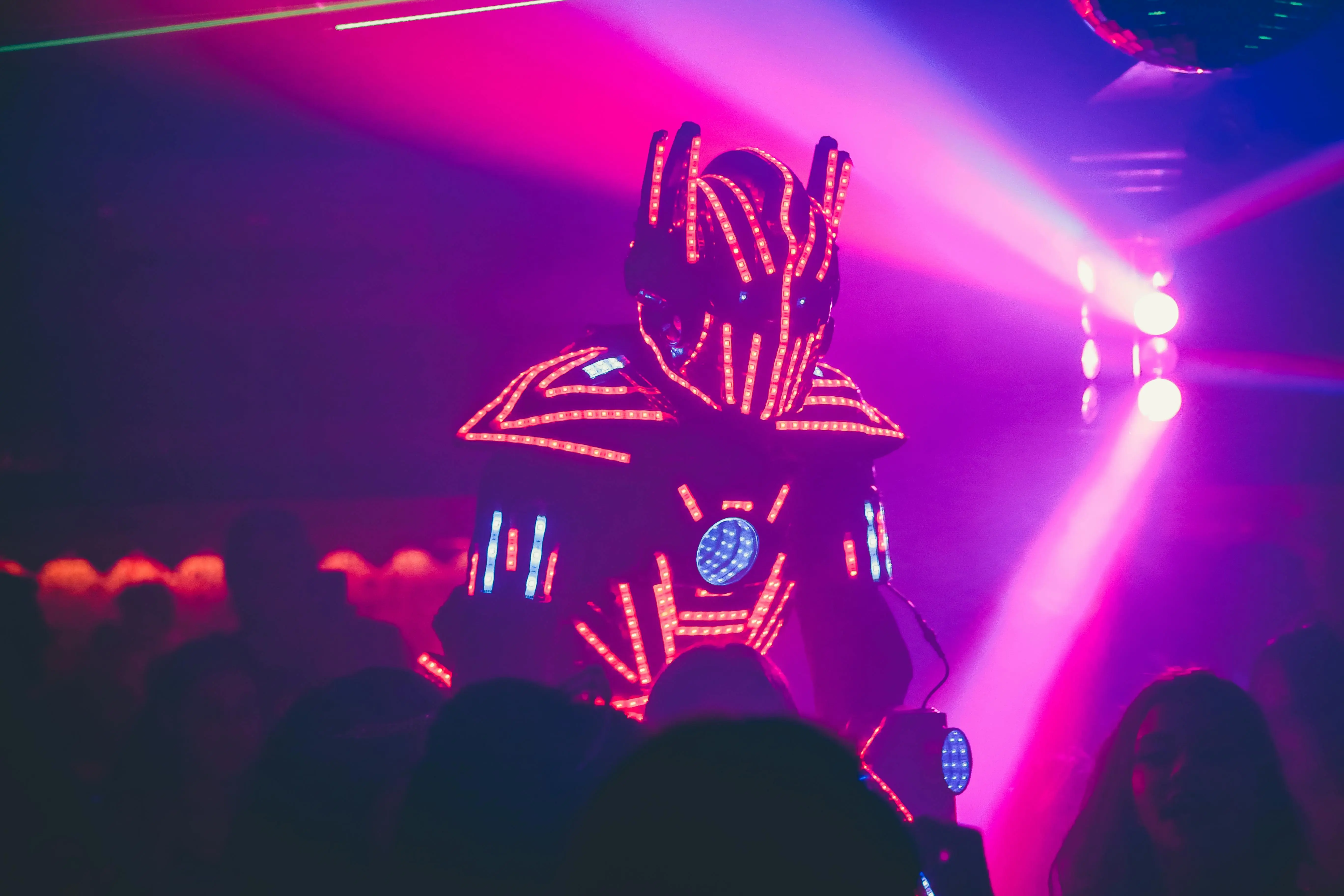 led outdoor spotlights Anonymous person in illuminated futuristic costume of robot performing show on stage of modern nightclub with neon illumination