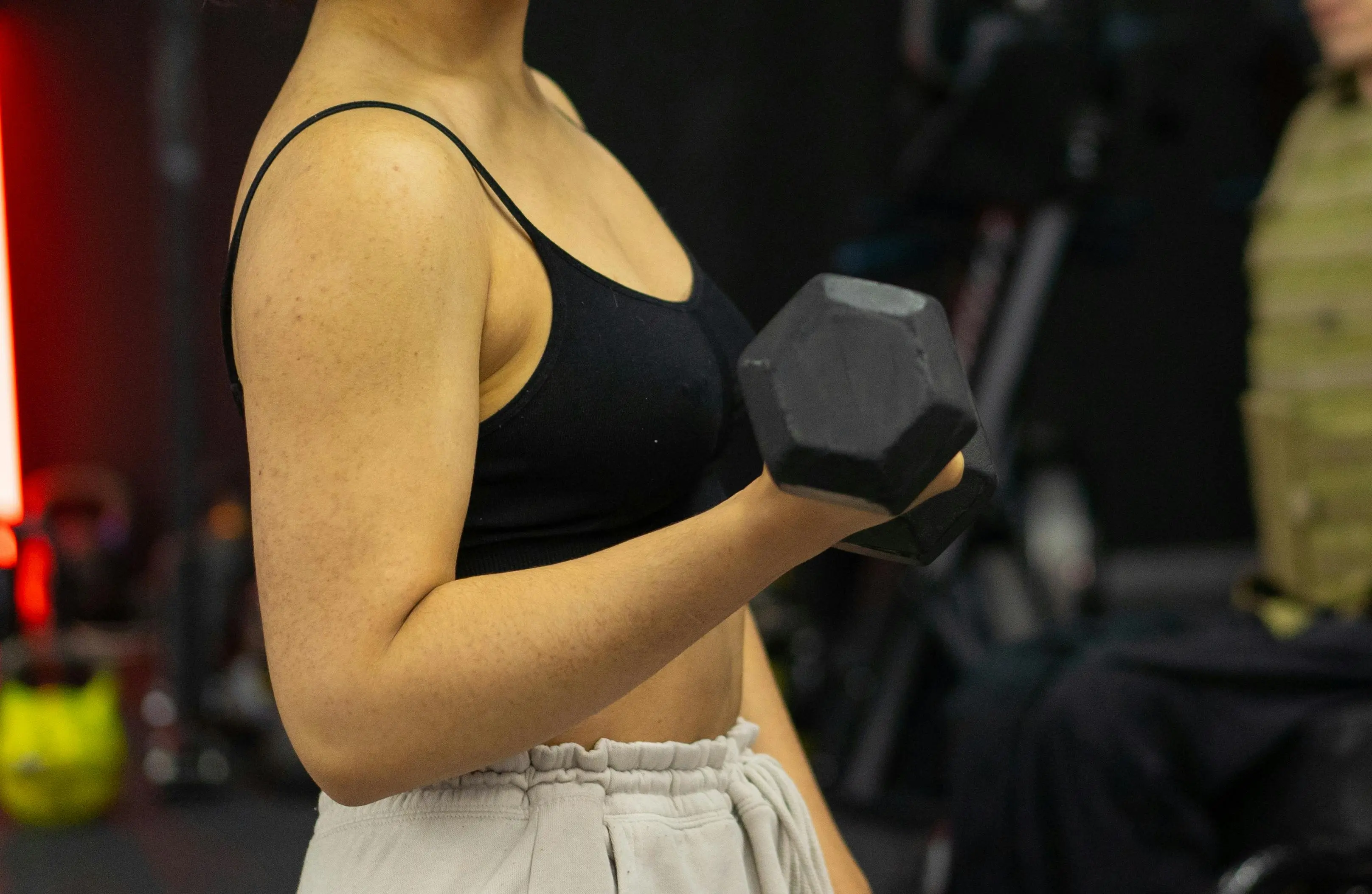 lift top cocktail table Focused woman lifting a dumbbell in a gym setting, promoting fitness and strength.
