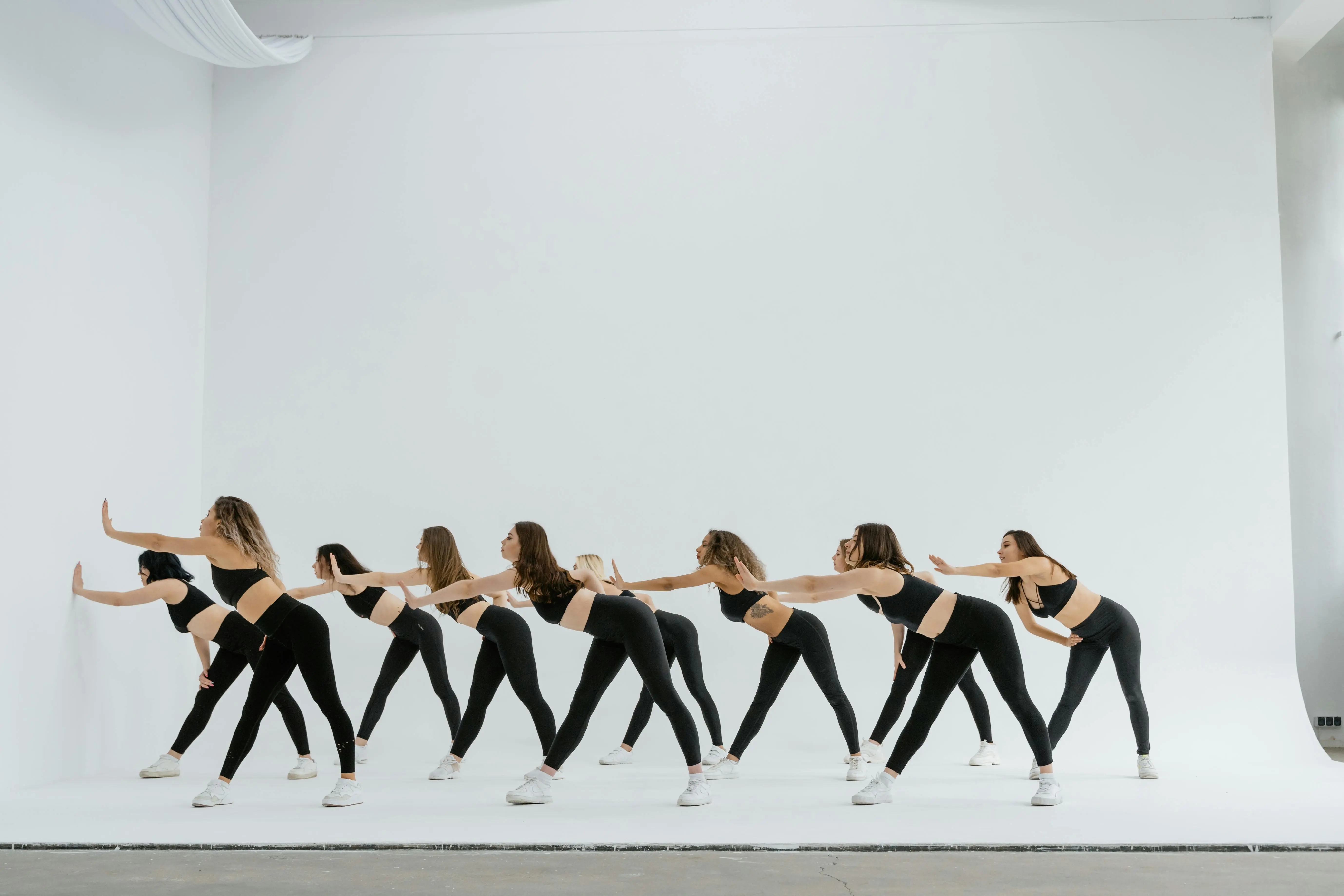 lift top cocktail table Group of women dancers performing choreography in a white studio setting.