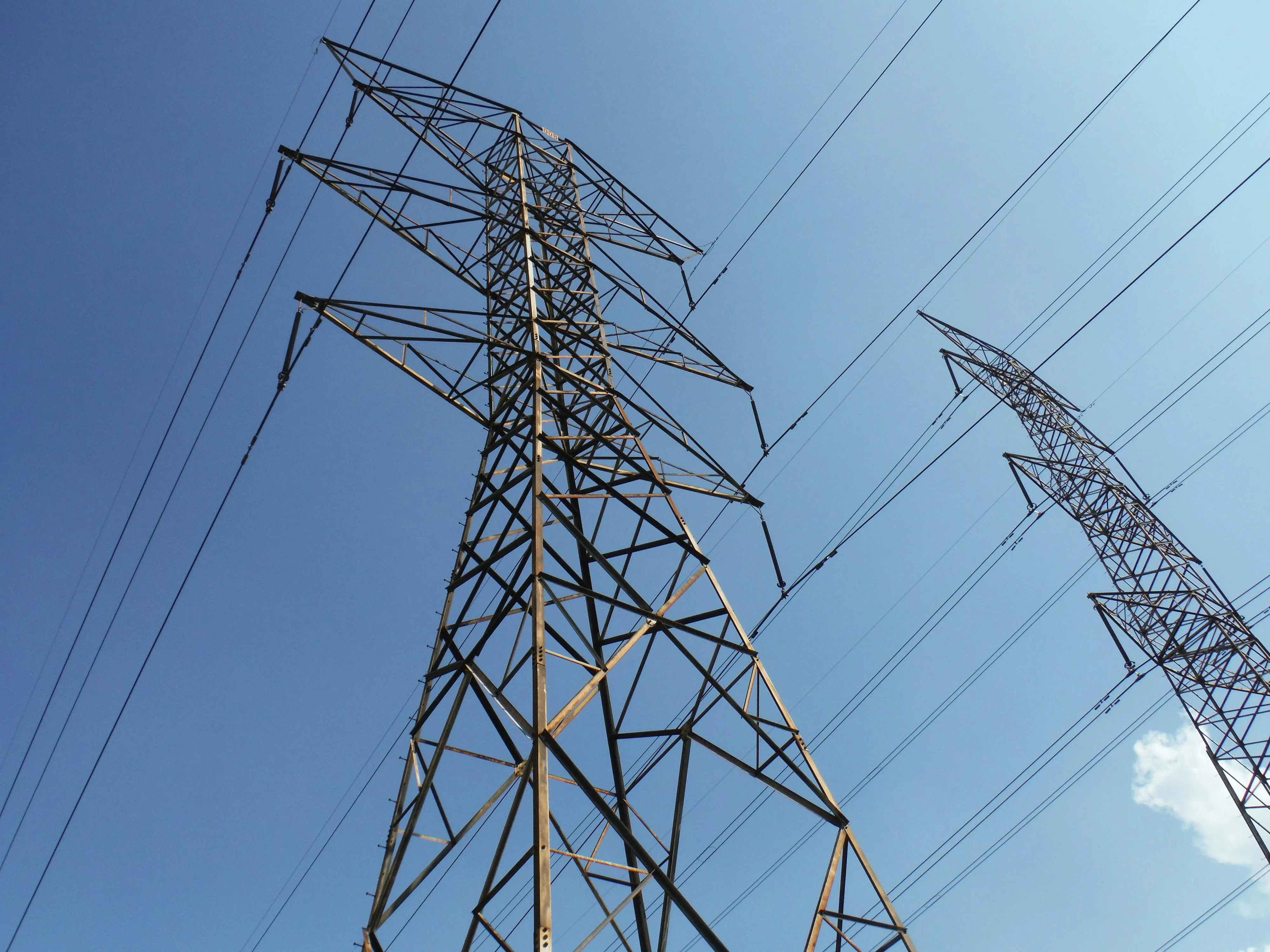 low voltage pathway lights Low angle view of towering electrical transmission lines and pylons under a clear blue sky, conveying energy and electricity concepts.