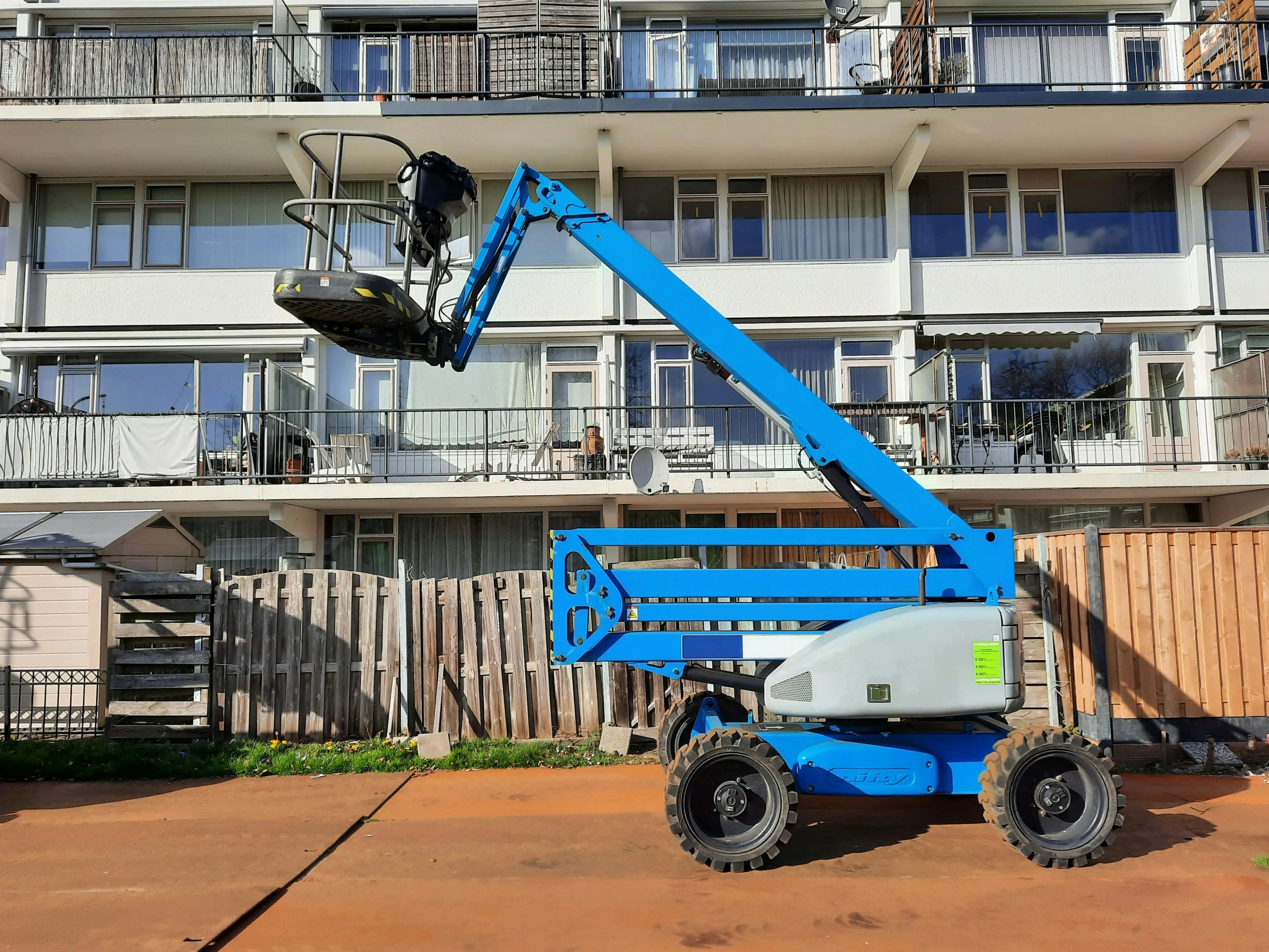 lift top cocktail table Blue construction lift in front of residential building under bright sunlight in Nederland.