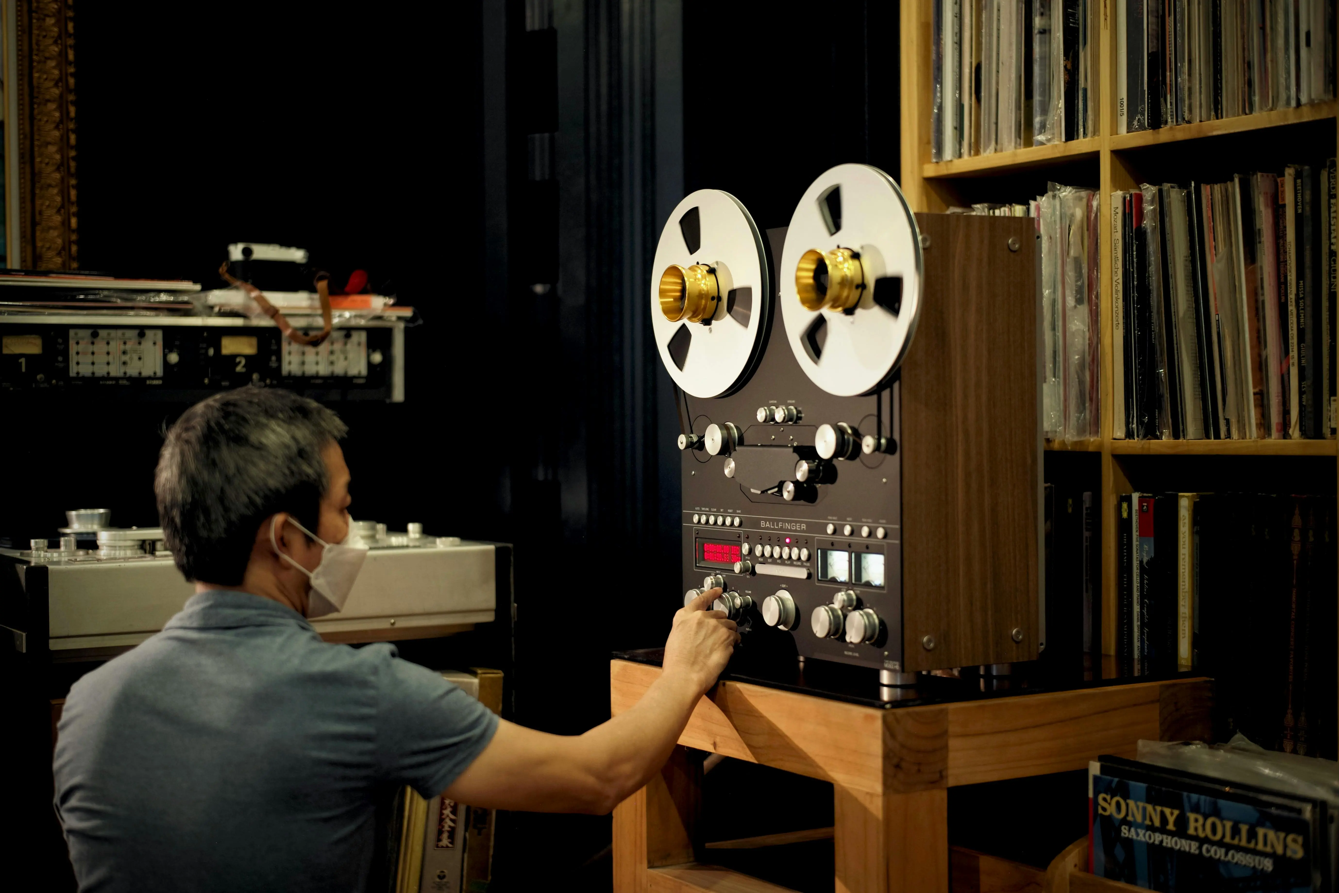 record storage cabinet A man adjusting a vintage reel-to-reel tape recorder in a library setting, focusing on analog sound technology.