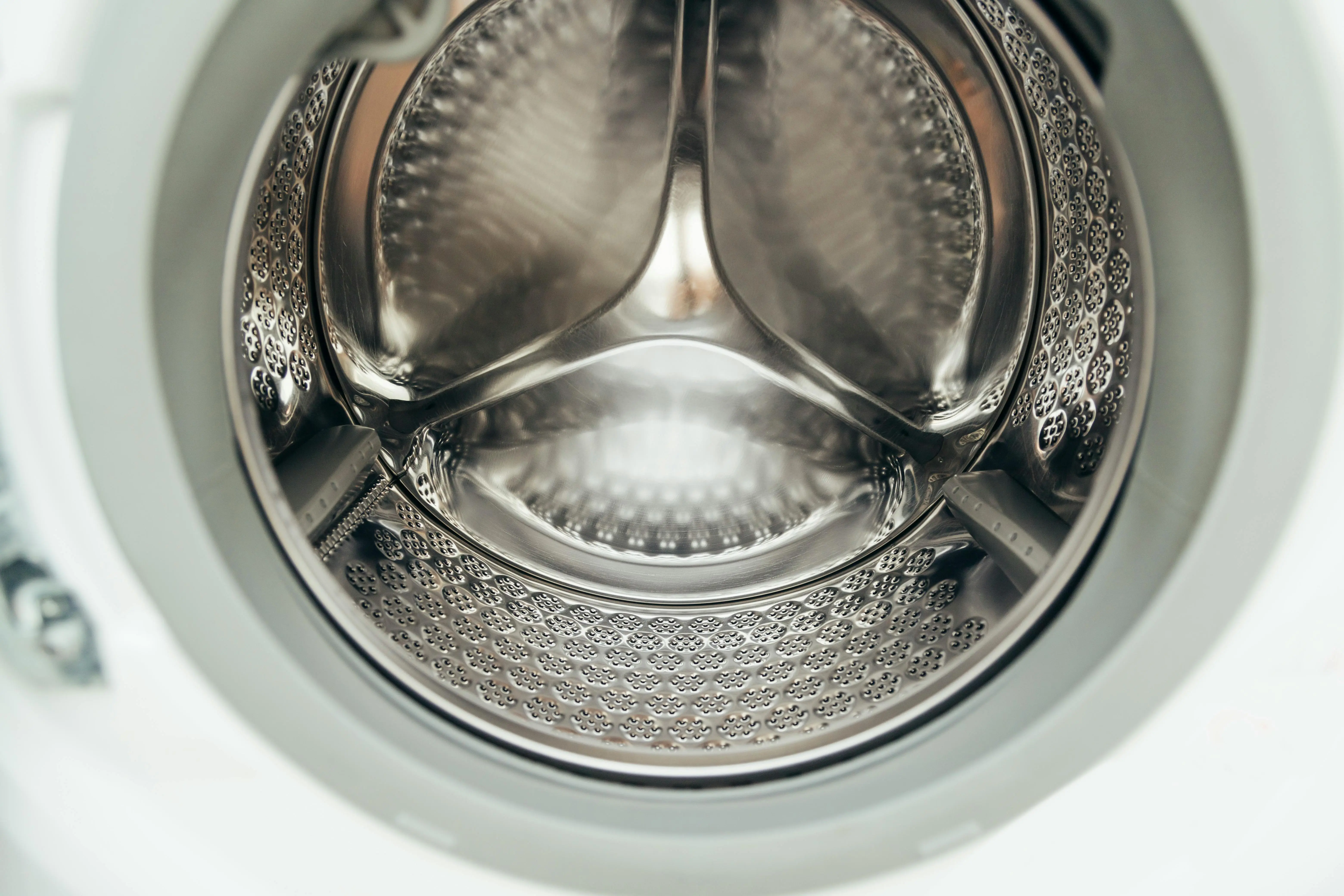 how to wash silk Detailed view of a clean, modern washing machine drum, showcasing shiny stainless steel interior.