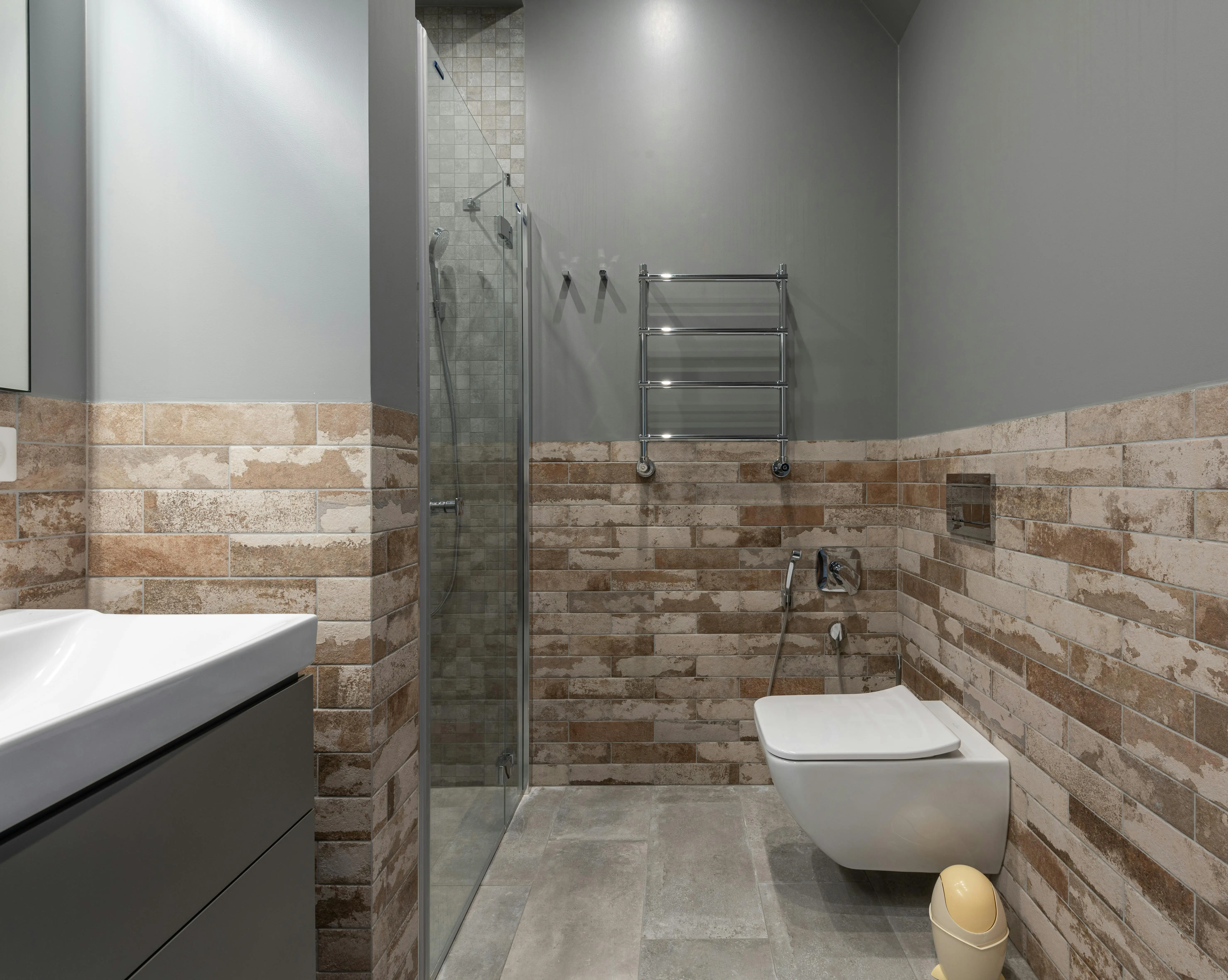 peel and stick stone tile Stylish contemporary bathroom featuring a glass shower and brick accent wall.