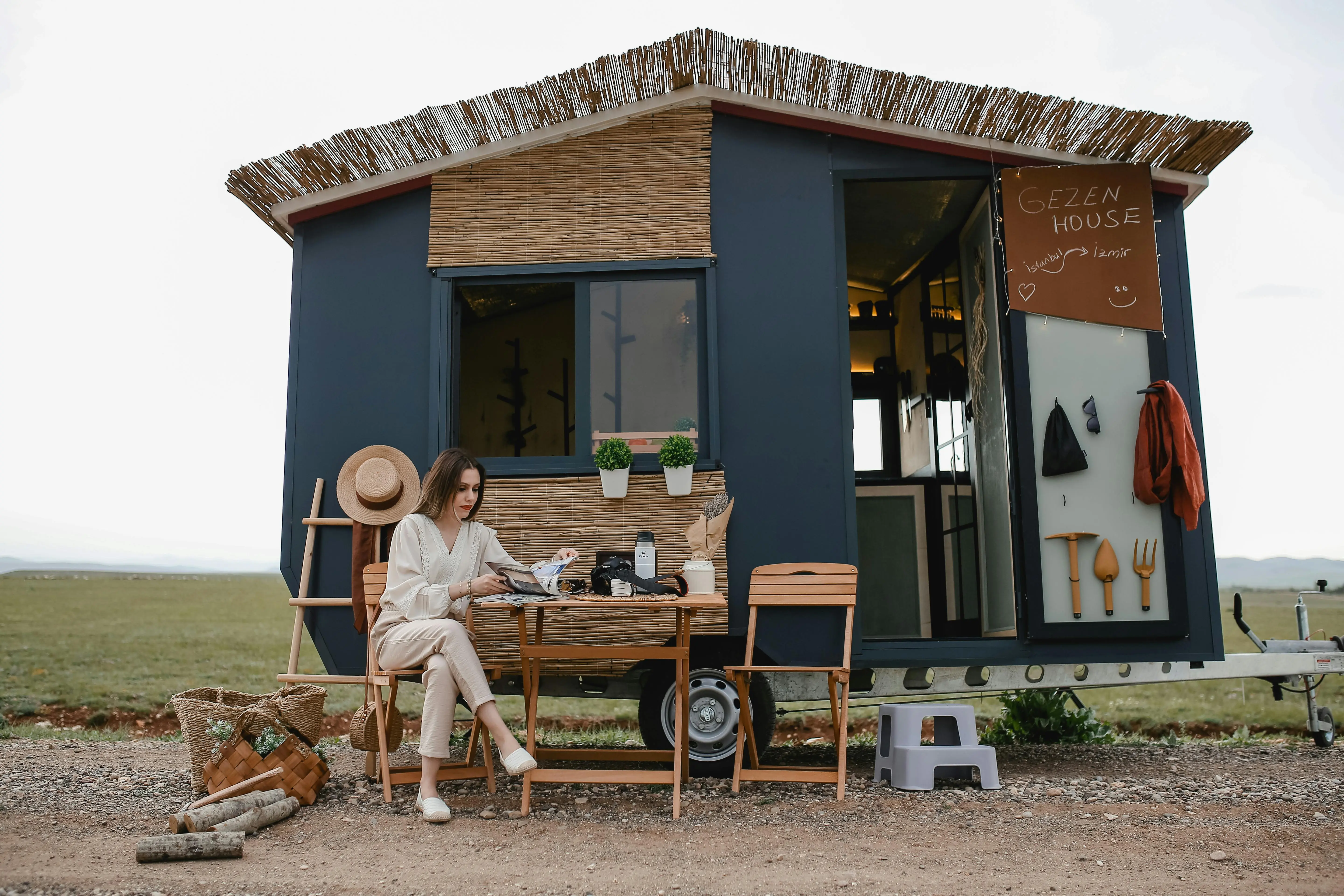 3 bedroom tiny house Woman sitting outside a boho-style mobile home, enjoying tranquility.