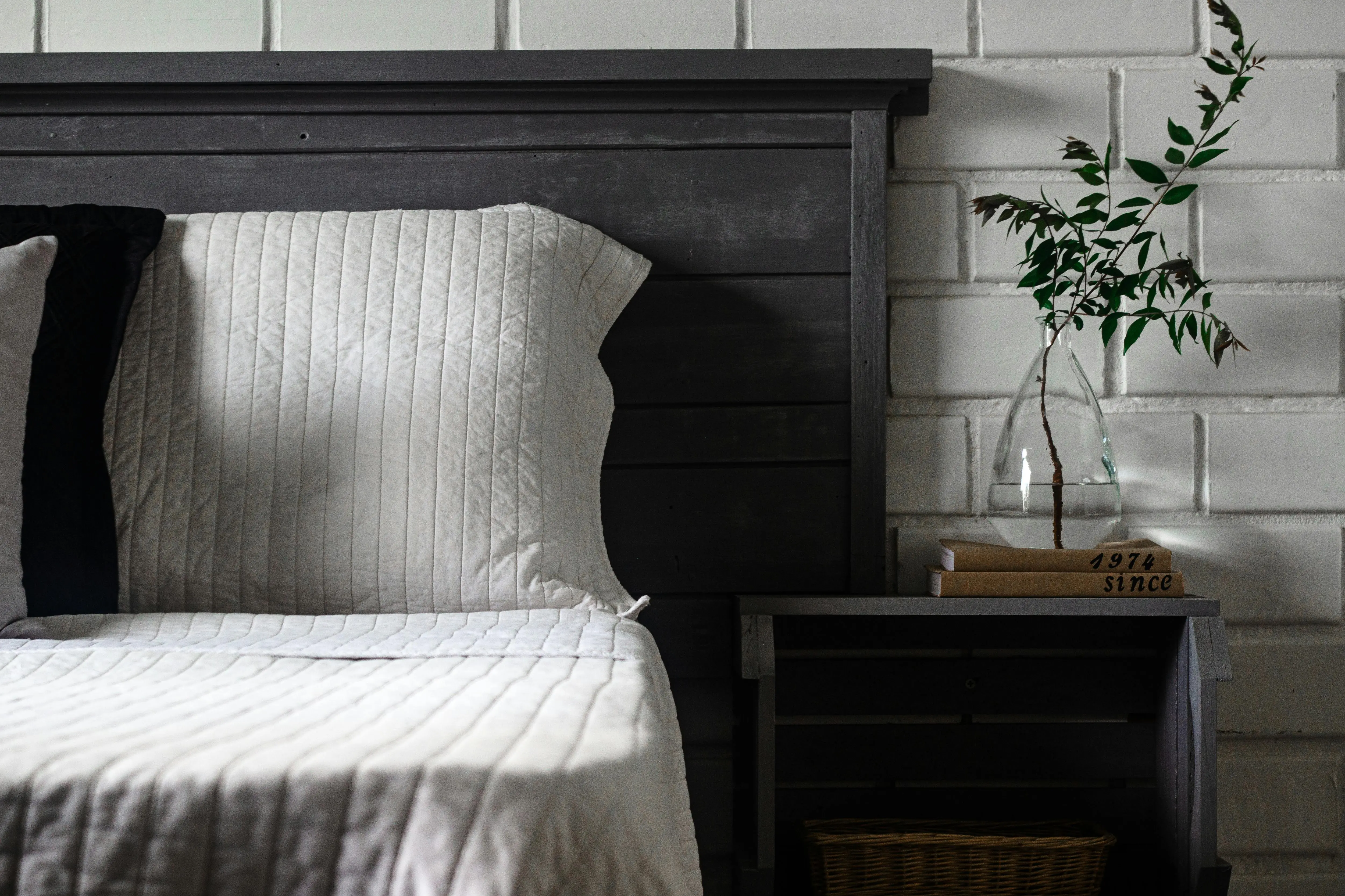 corner bed design Chic rustic bedroom with cozy bedding, modern nightstand and glass vase.