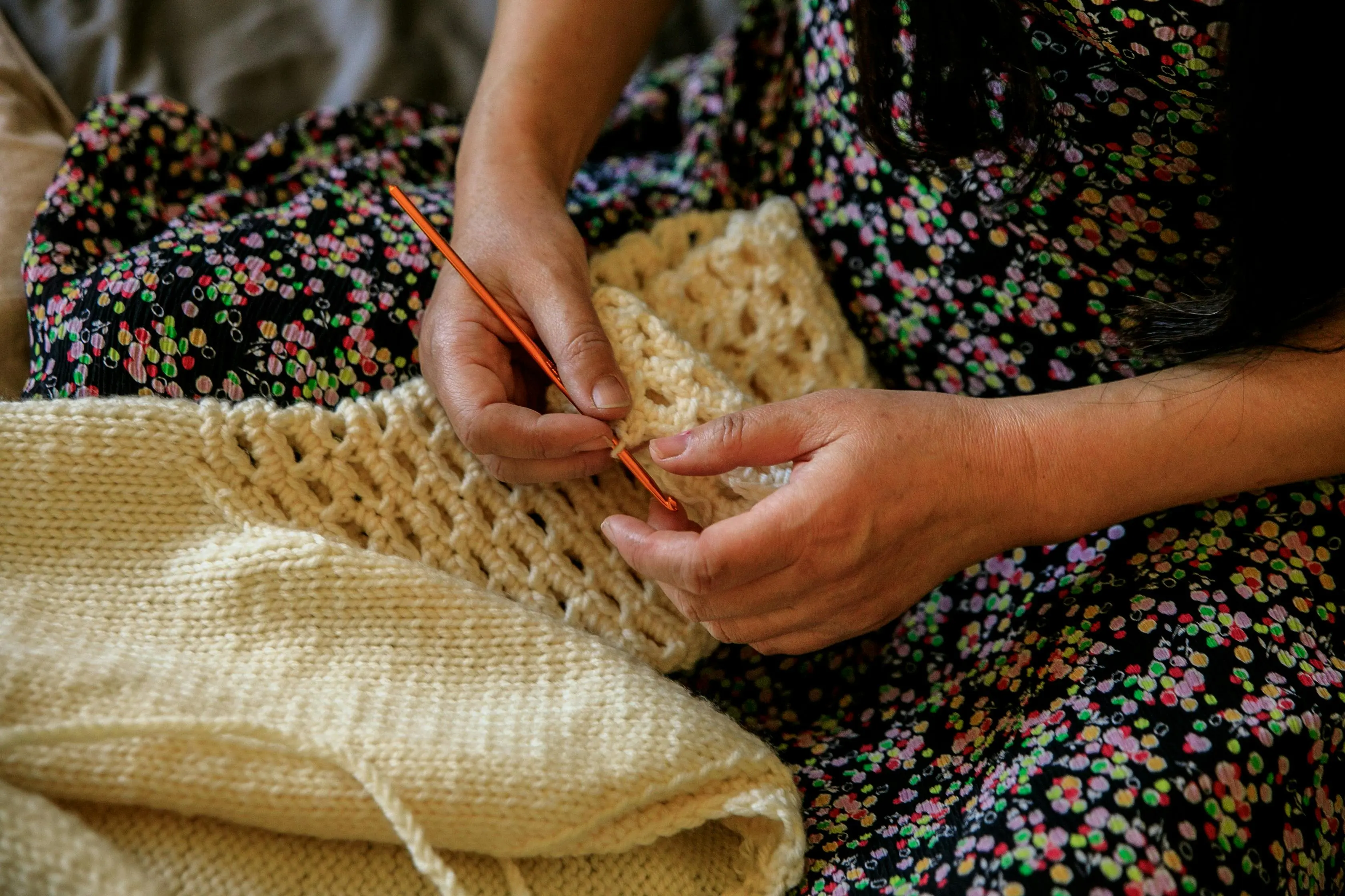 diy small craft room ideas Close-up of woman crocheting a handmade garment with careful attention.