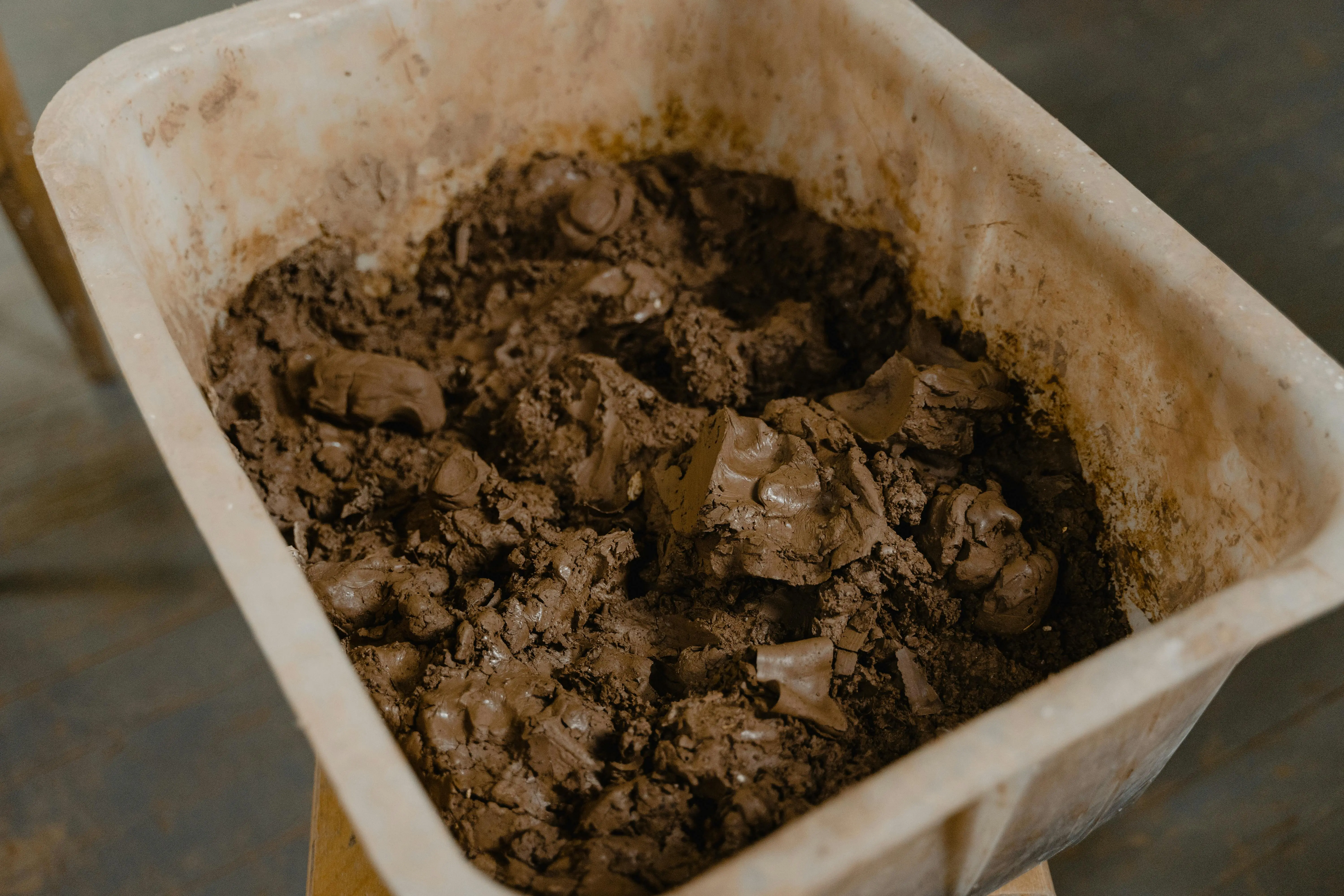 what to put around foundation of house A detailed view of wet clay inside a large plastic container, ideal for pottery or sculpture.