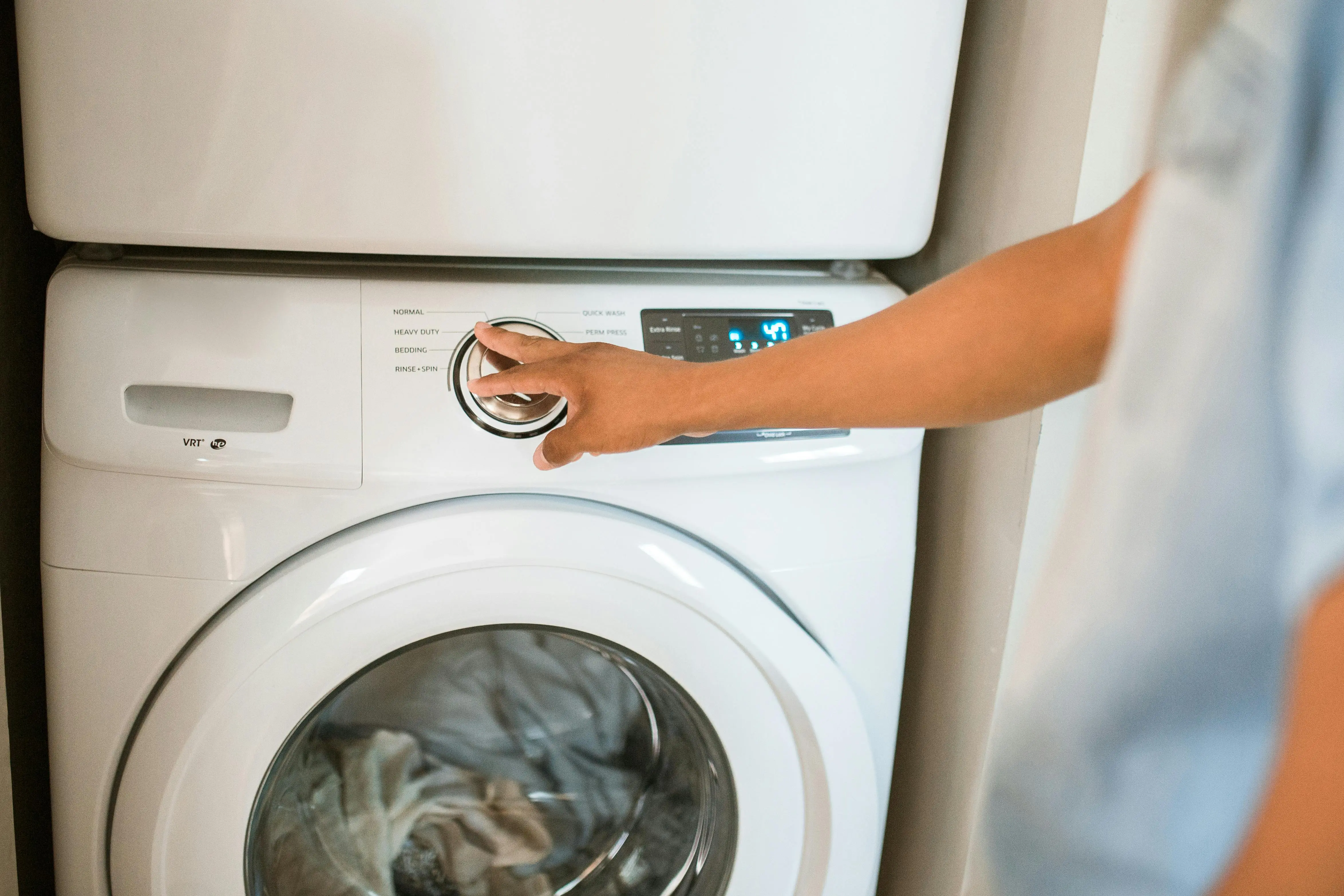 rv stackable washer and dryer Close-up of a person adjusting a washing machine in a modern laundry room.