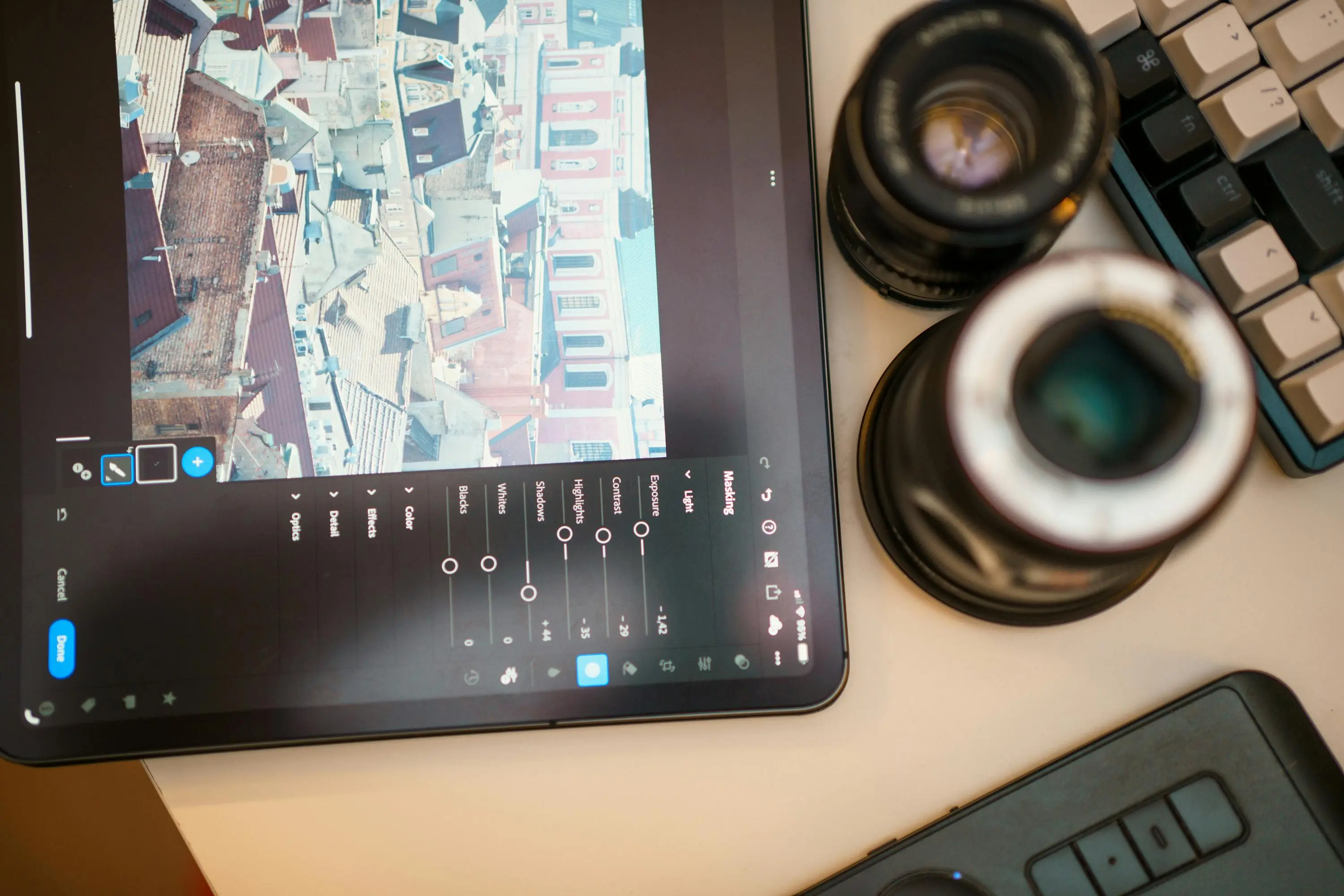 adjustable height coffee dining table A modern workspace featuring a tablet editing cityscape photo, camera lens, and keyboard.