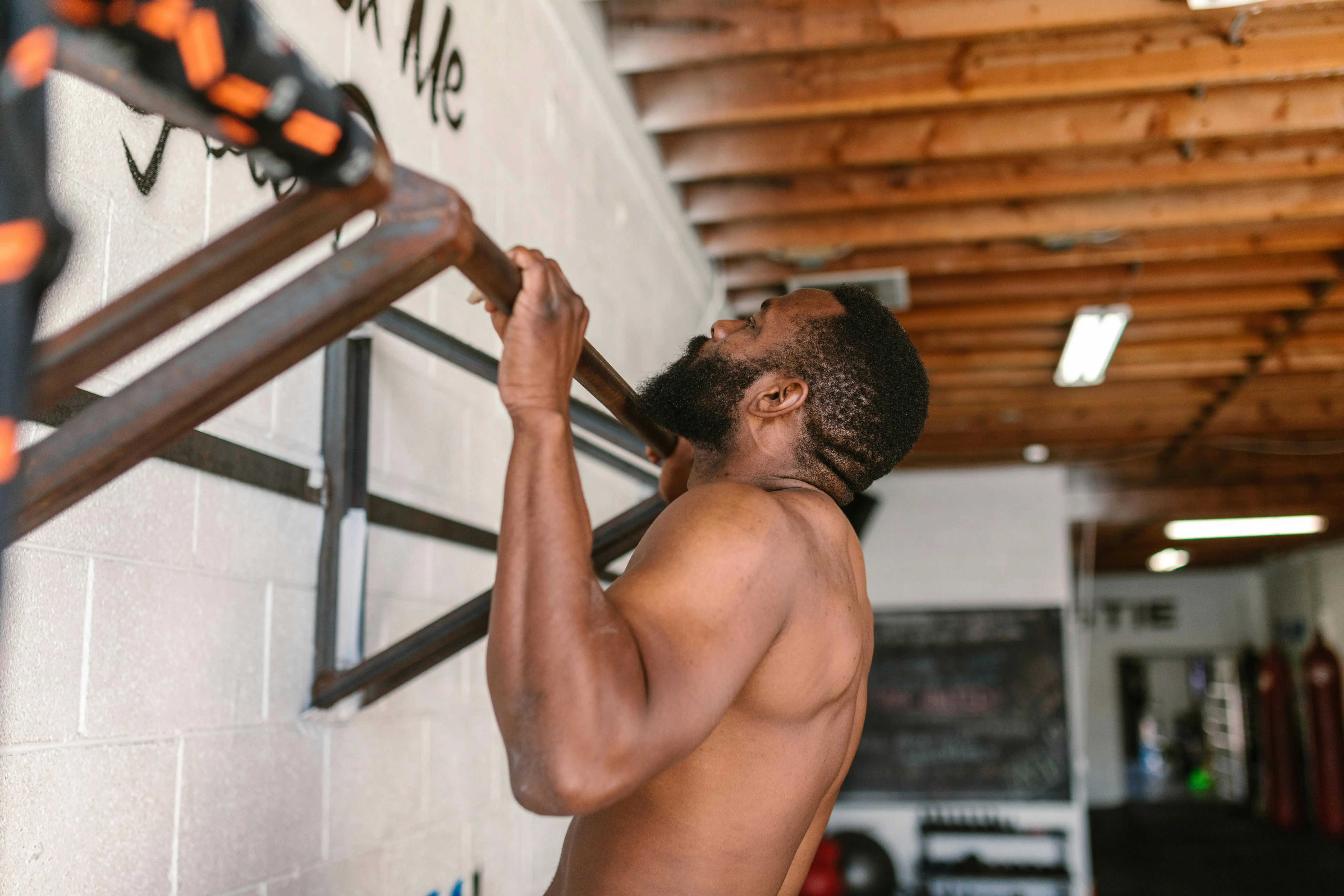 black drawer pulls A shirtless man doing a pull-up exercise on a pull-up bar.