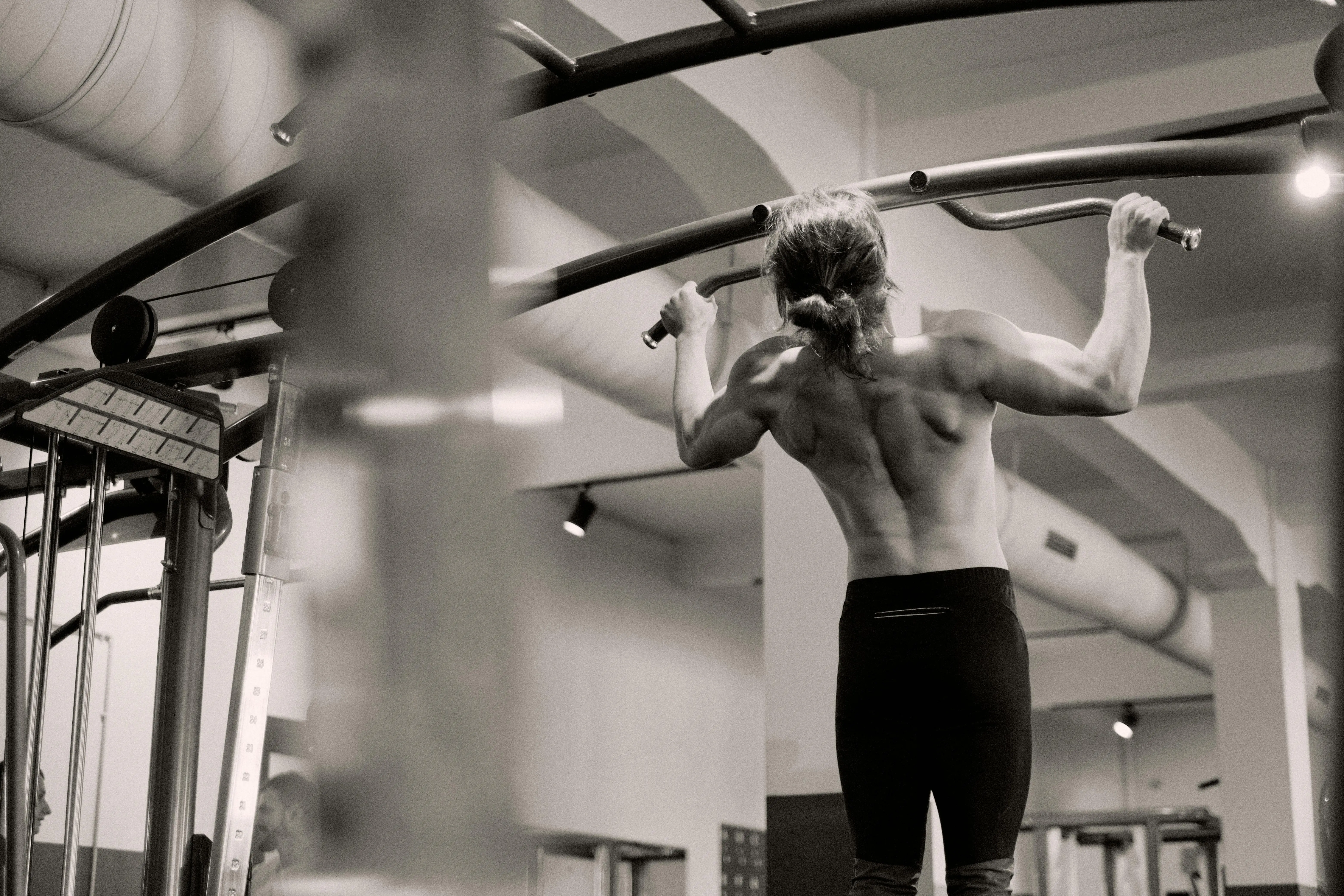 black drawer pulls Focused on a man doing pull-ups in a gym, showcasing strength and fitness.