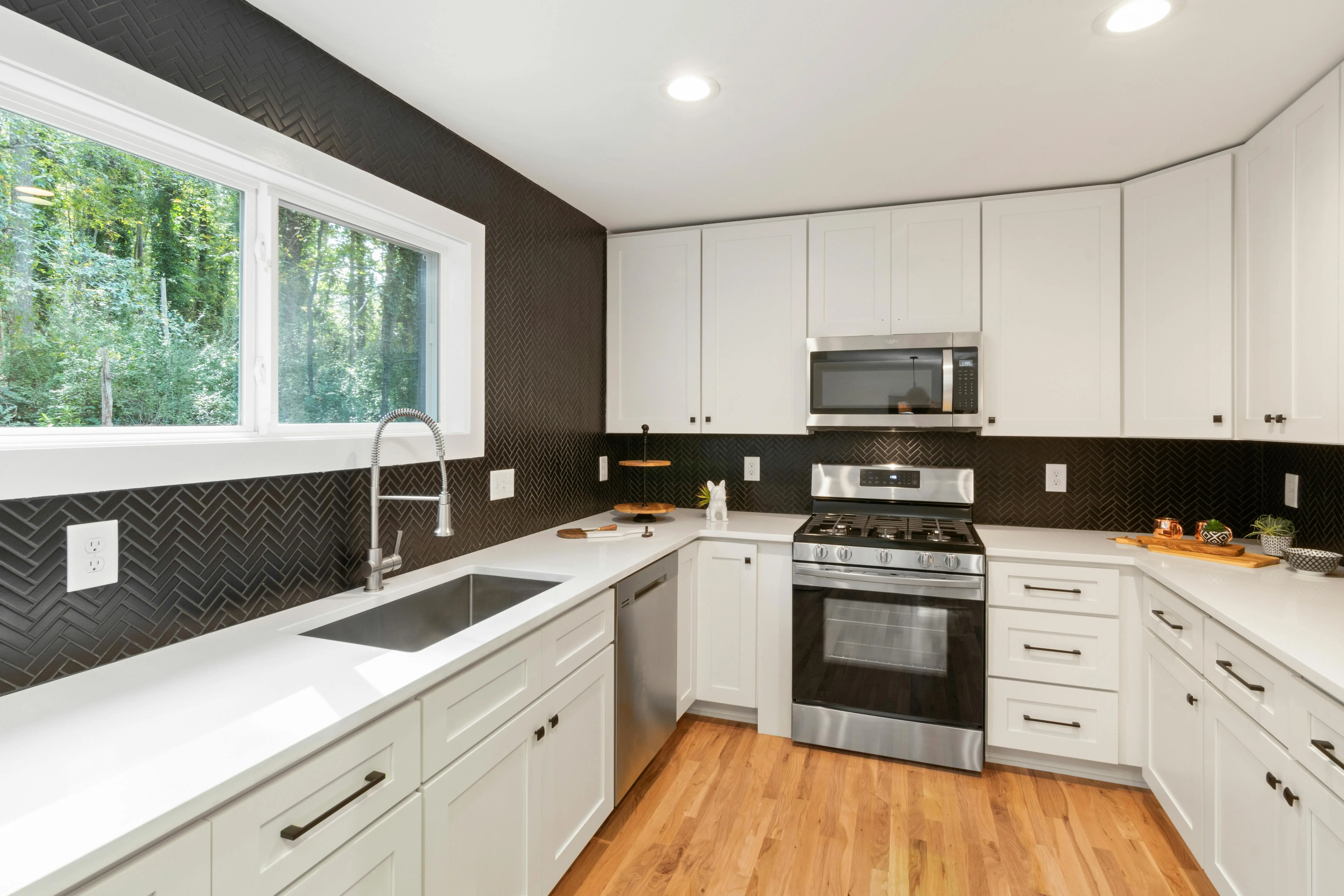 black and white backsplash Stylish modern kitchen featuring white cabinets, stainless steel appliances, and wooden flooring.