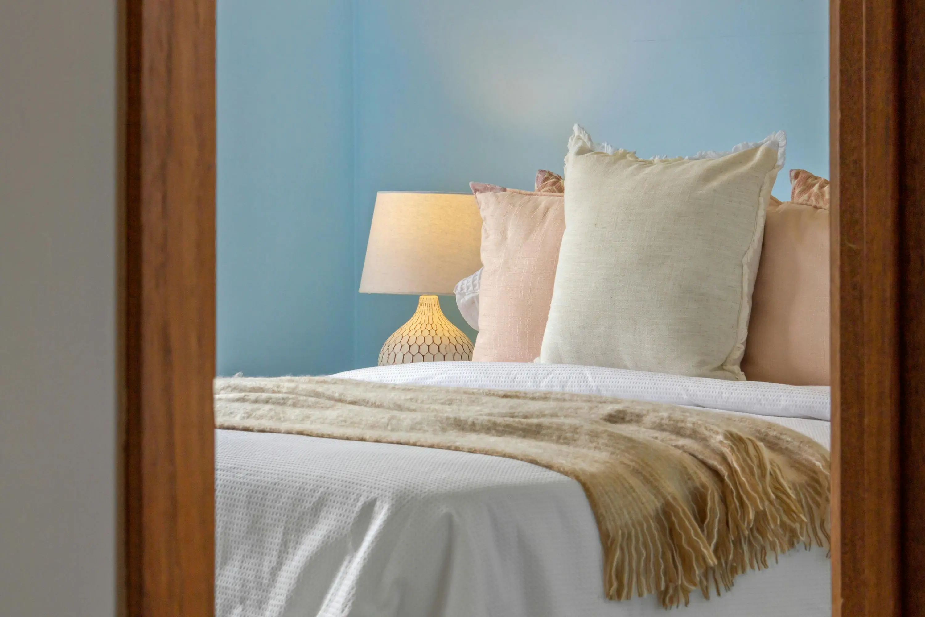 blue pillows A serene bedroom scene featuring blue walls, decorative pillows, and soft lighting for a cozy ambiance.